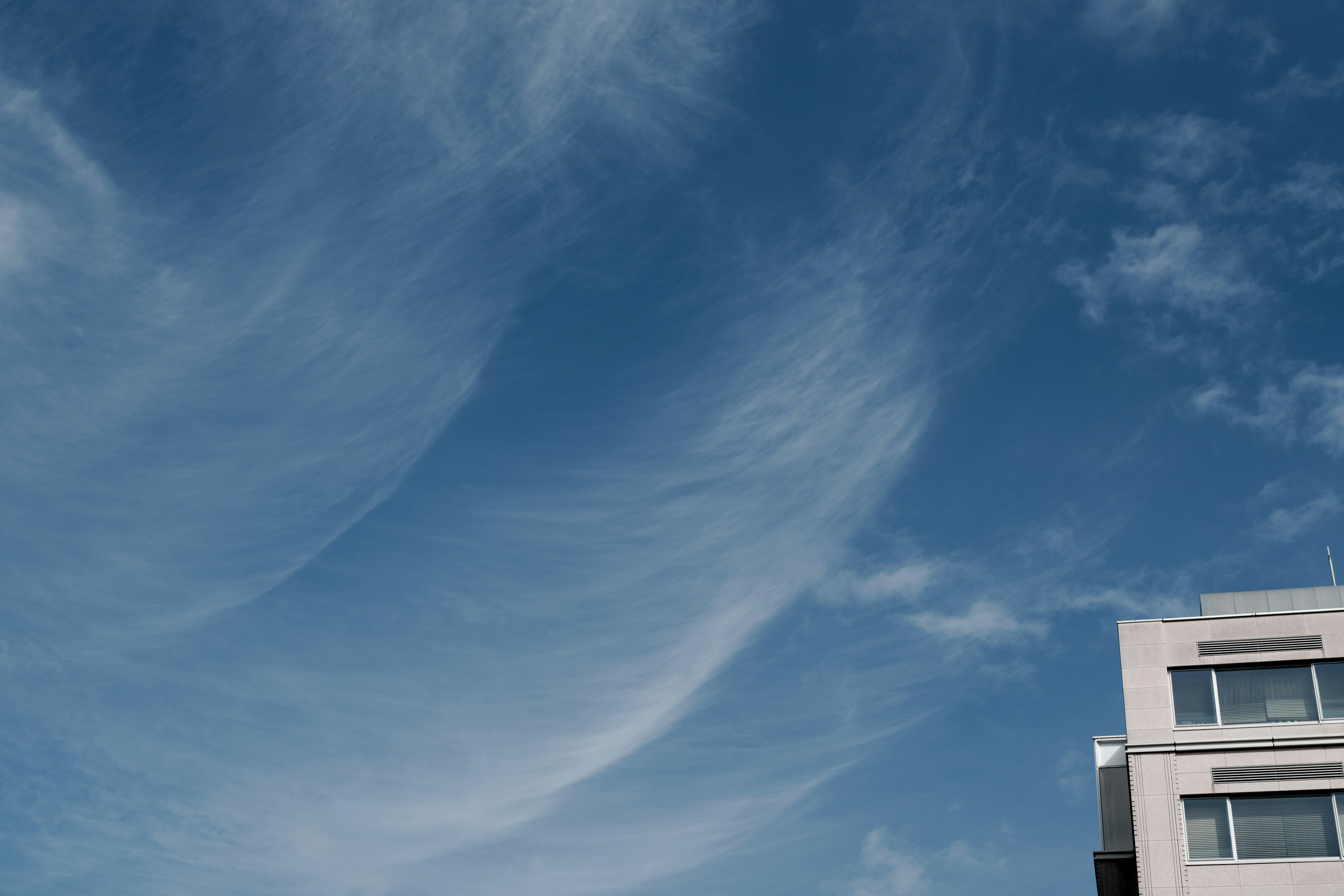 Langit biru dengan awan putih dan bagian dari bangunan modern