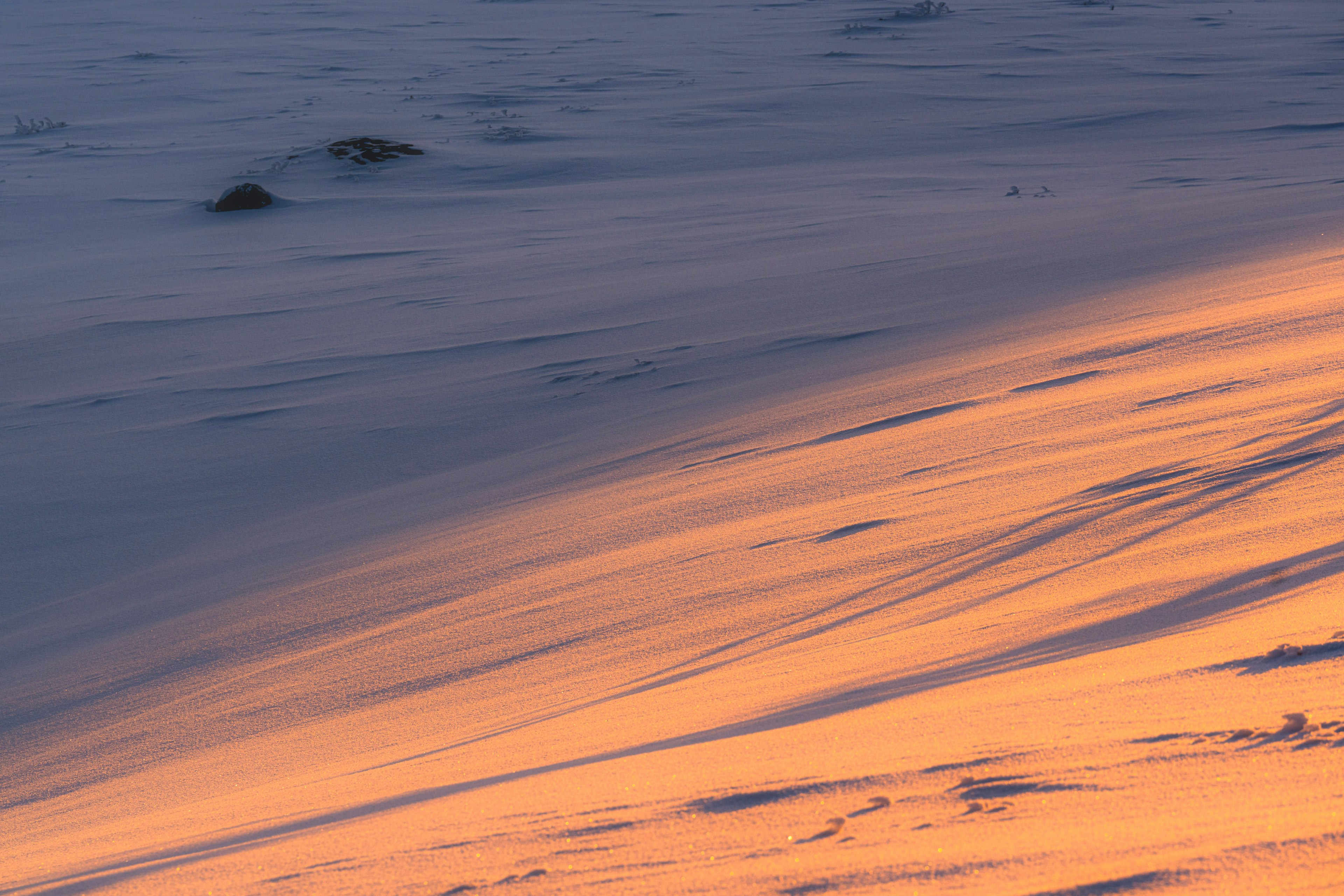 Eine ruhige Landschaft mit warmen Sonnenuntergangsfarben, die sich auf einer verschneiten Oberfläche spiegeln