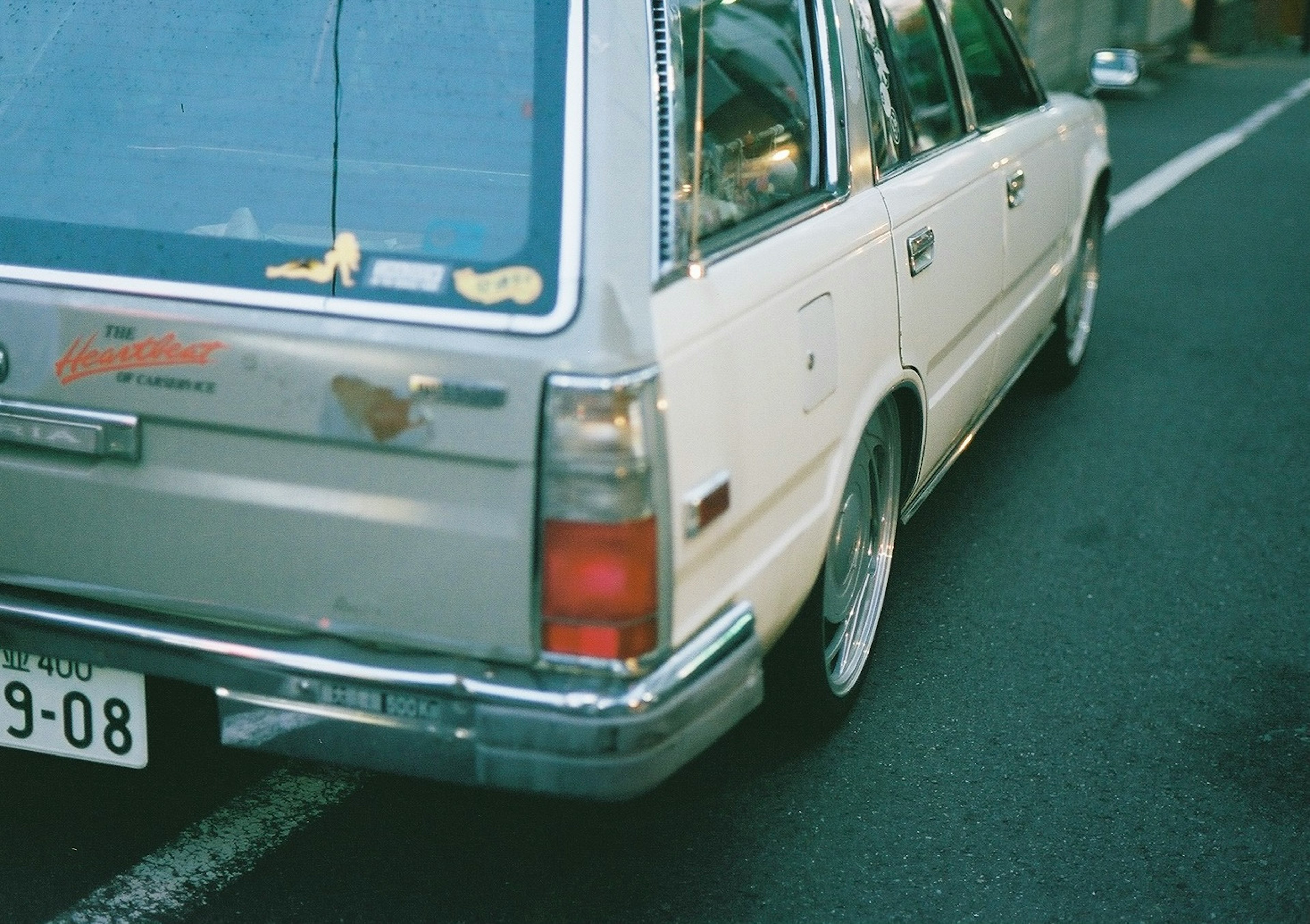 銀色のワゴン車の後部にステッカーとナンバープレートがある