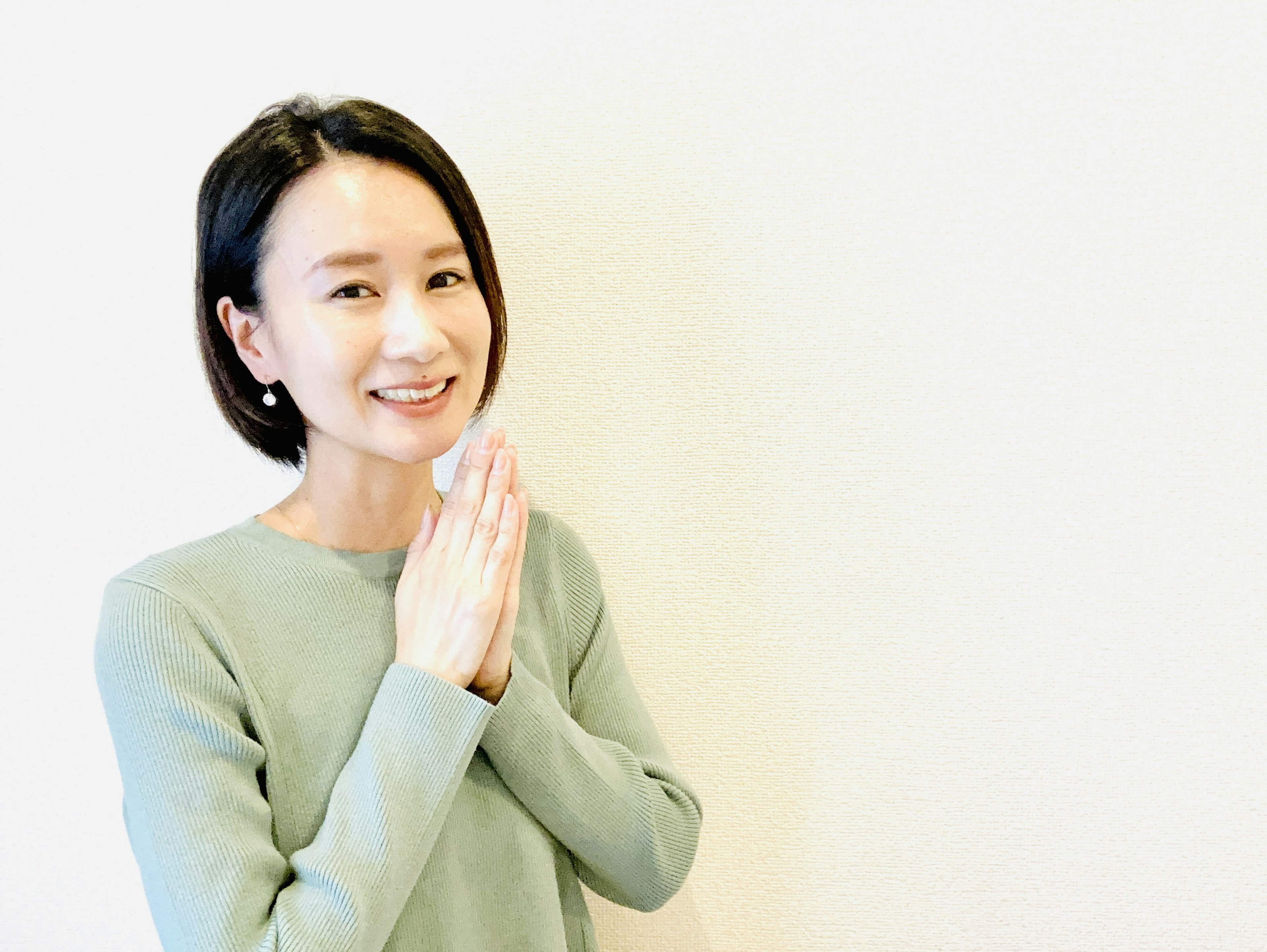 A woman smiling with hands together in a greeting gesture