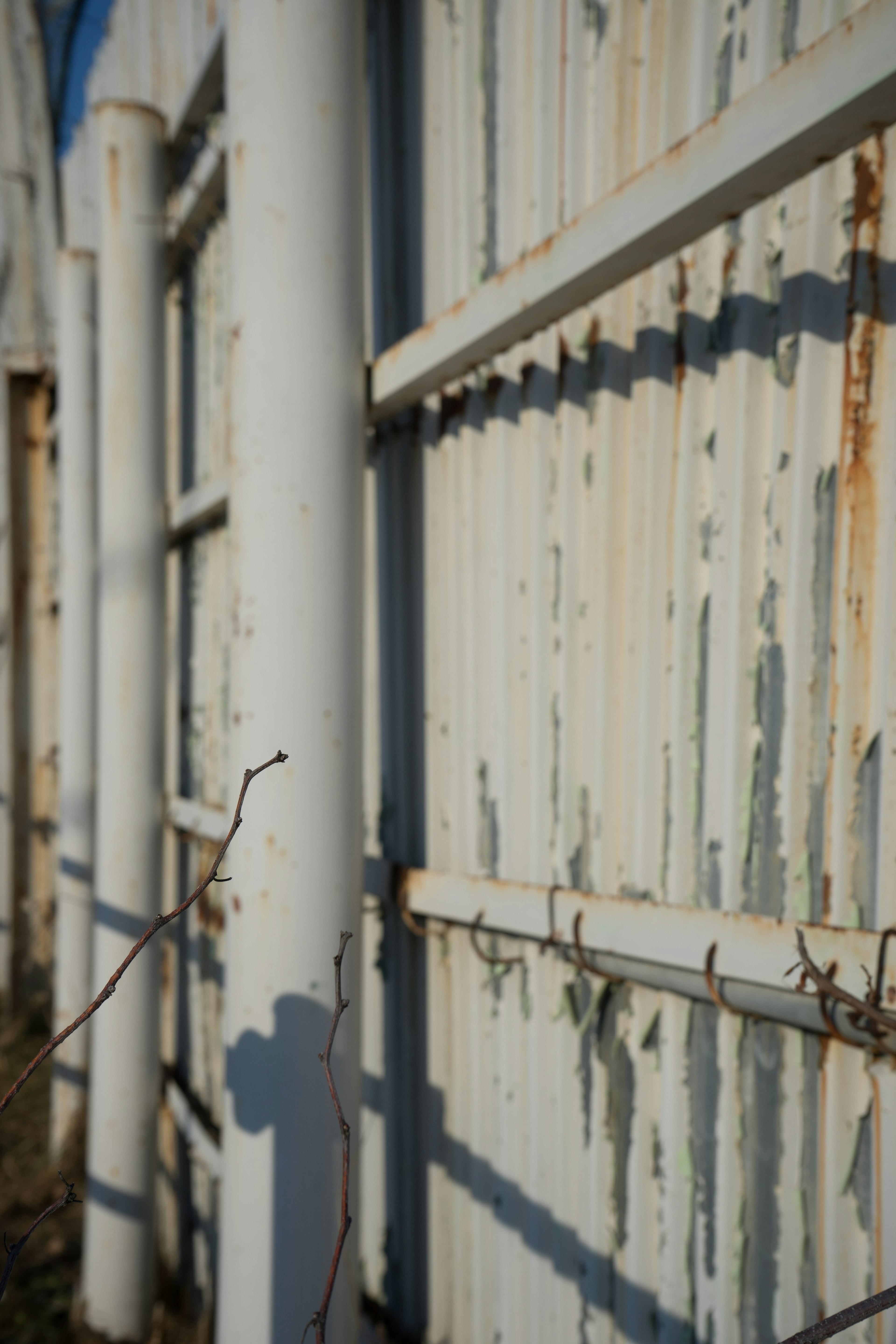 Rusty metal wall with white pipes and peeling paint