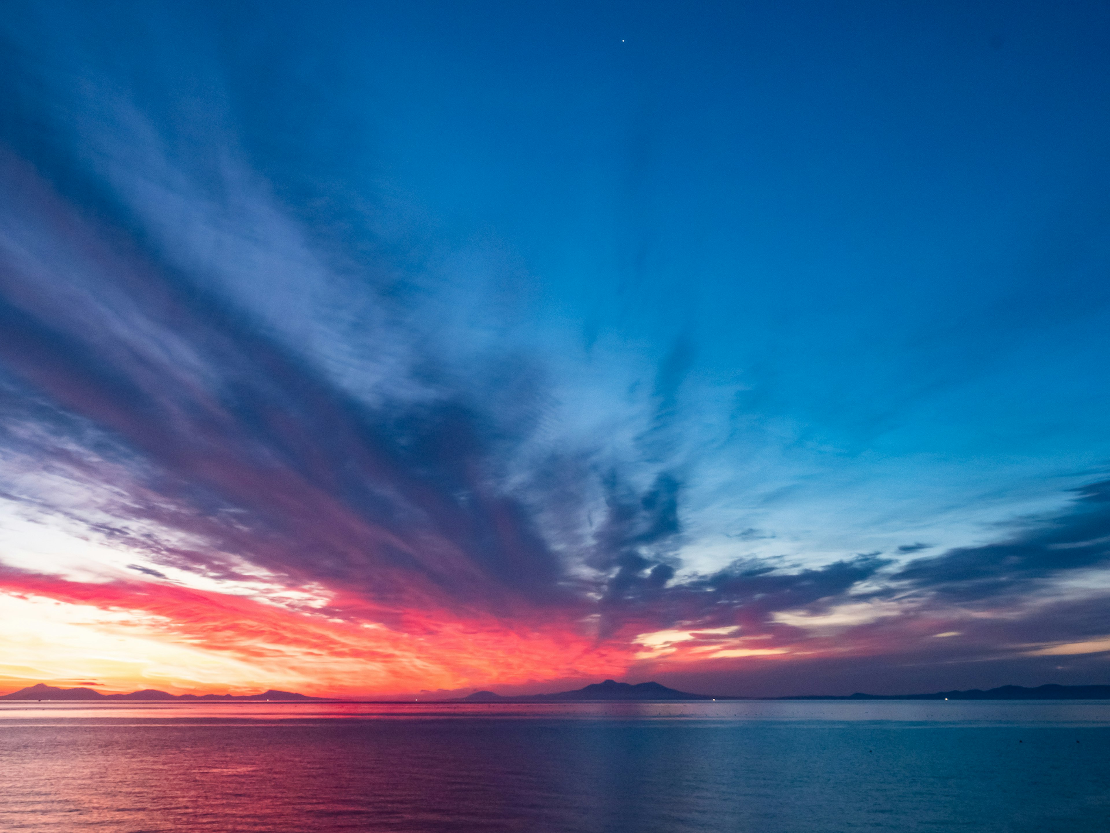 Stupendo cielo al tramonto con sfumature di blu e rosso sopra l'oceano