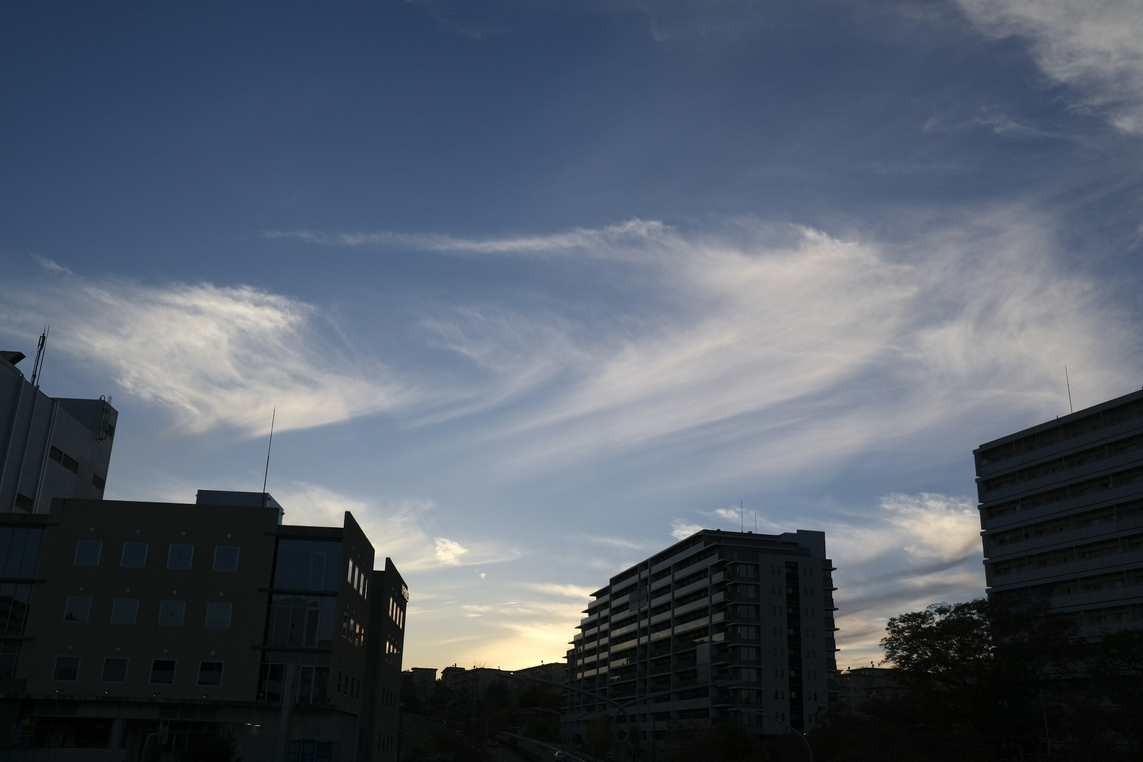 Silhouette of buildings against a blue sky with wispy clouds