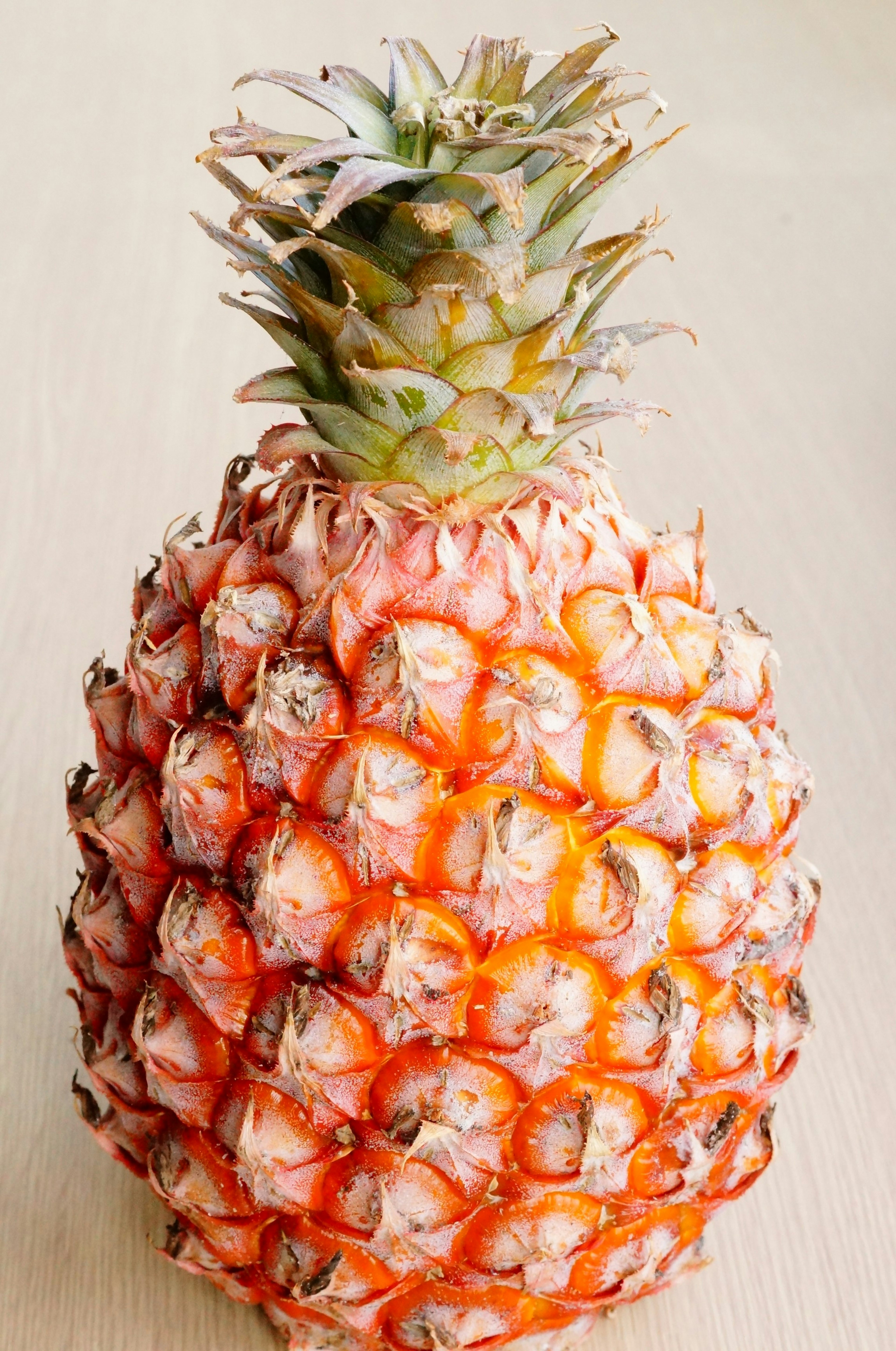 Una piña naranja vibrante colocada sobre una mesa de madera