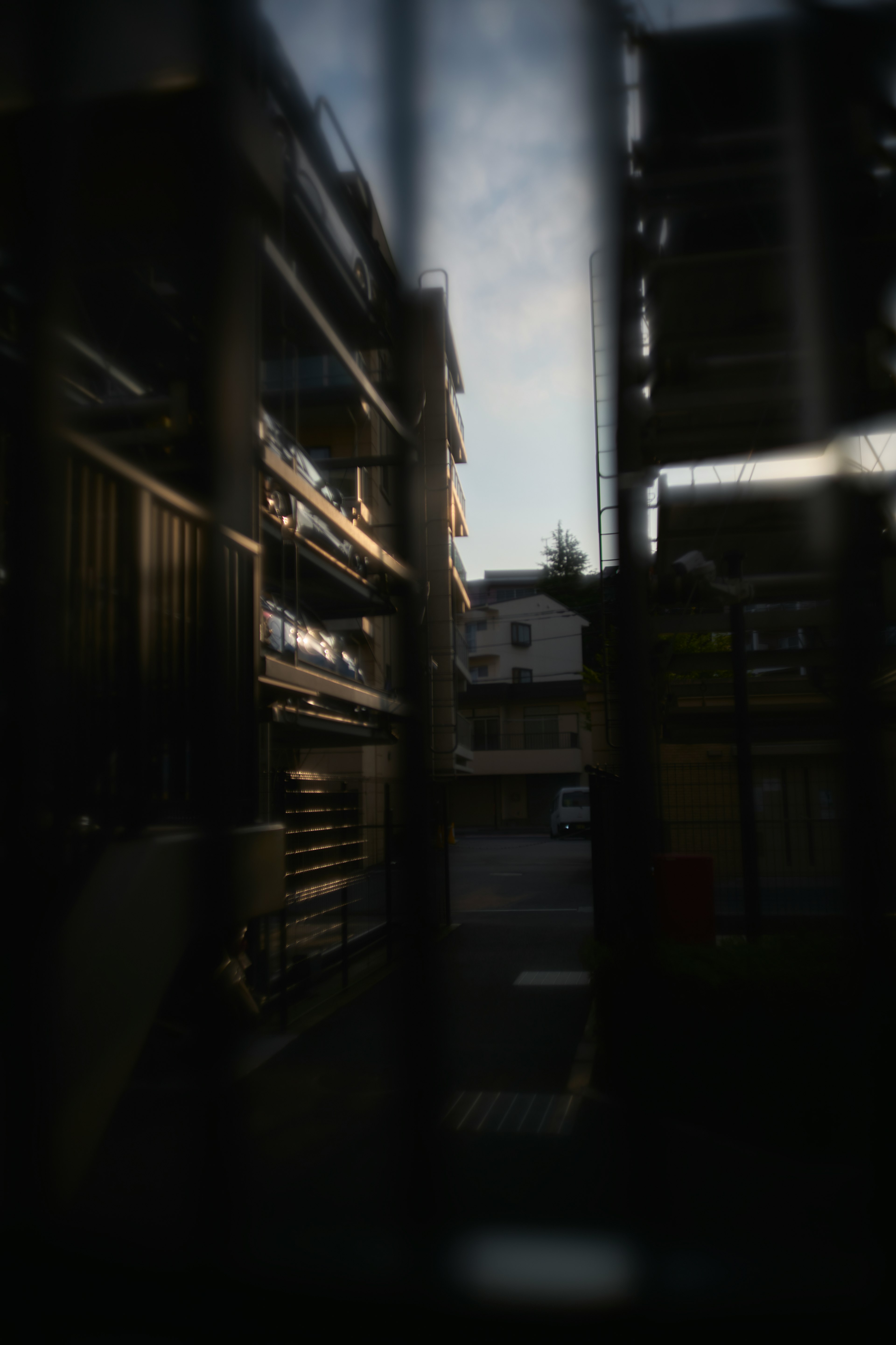 Dimly lit scene featuring shelves with a house visible in the background