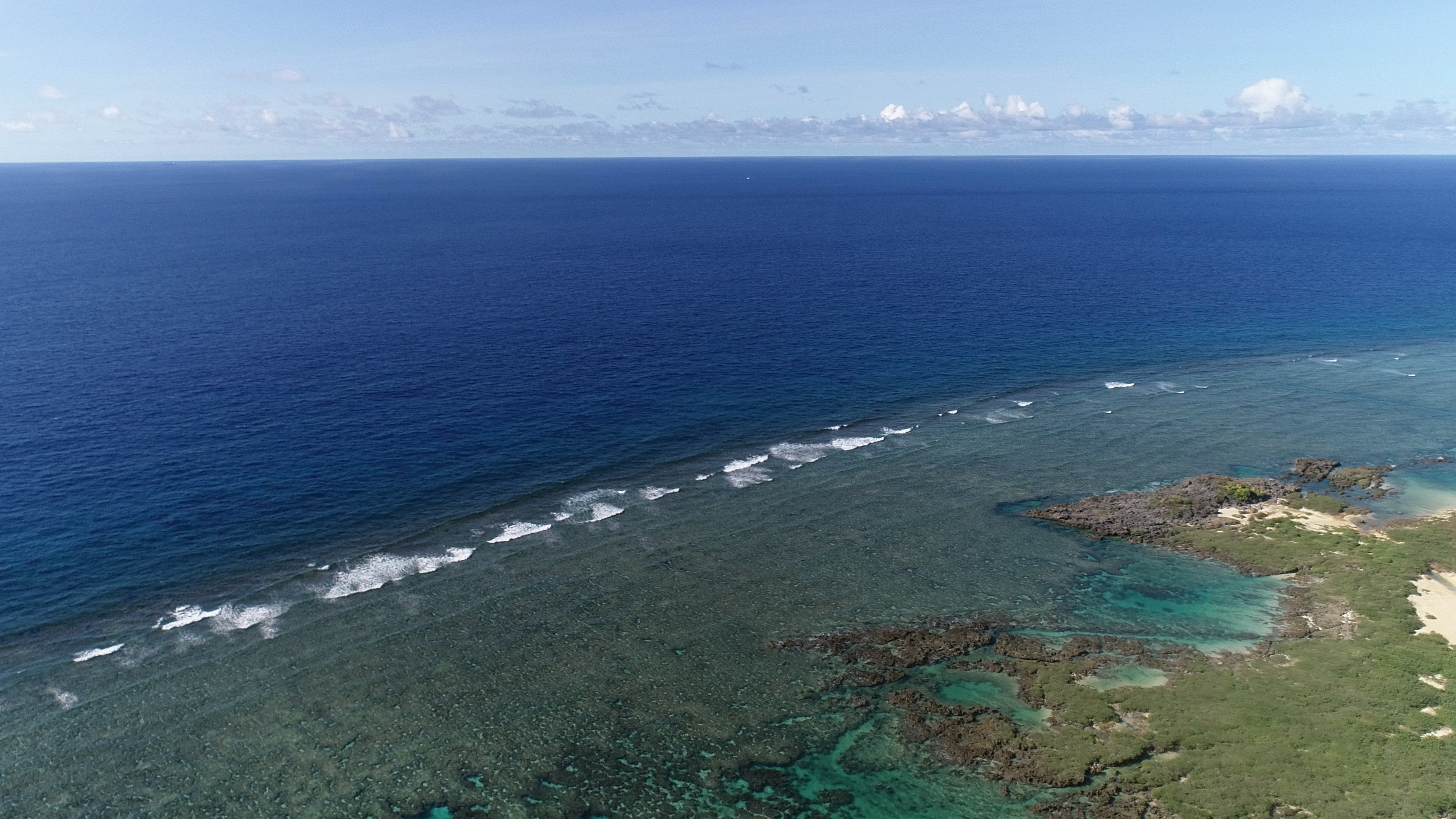 Vista aérea de un océano azul con arrecifes de coral y playas de arena