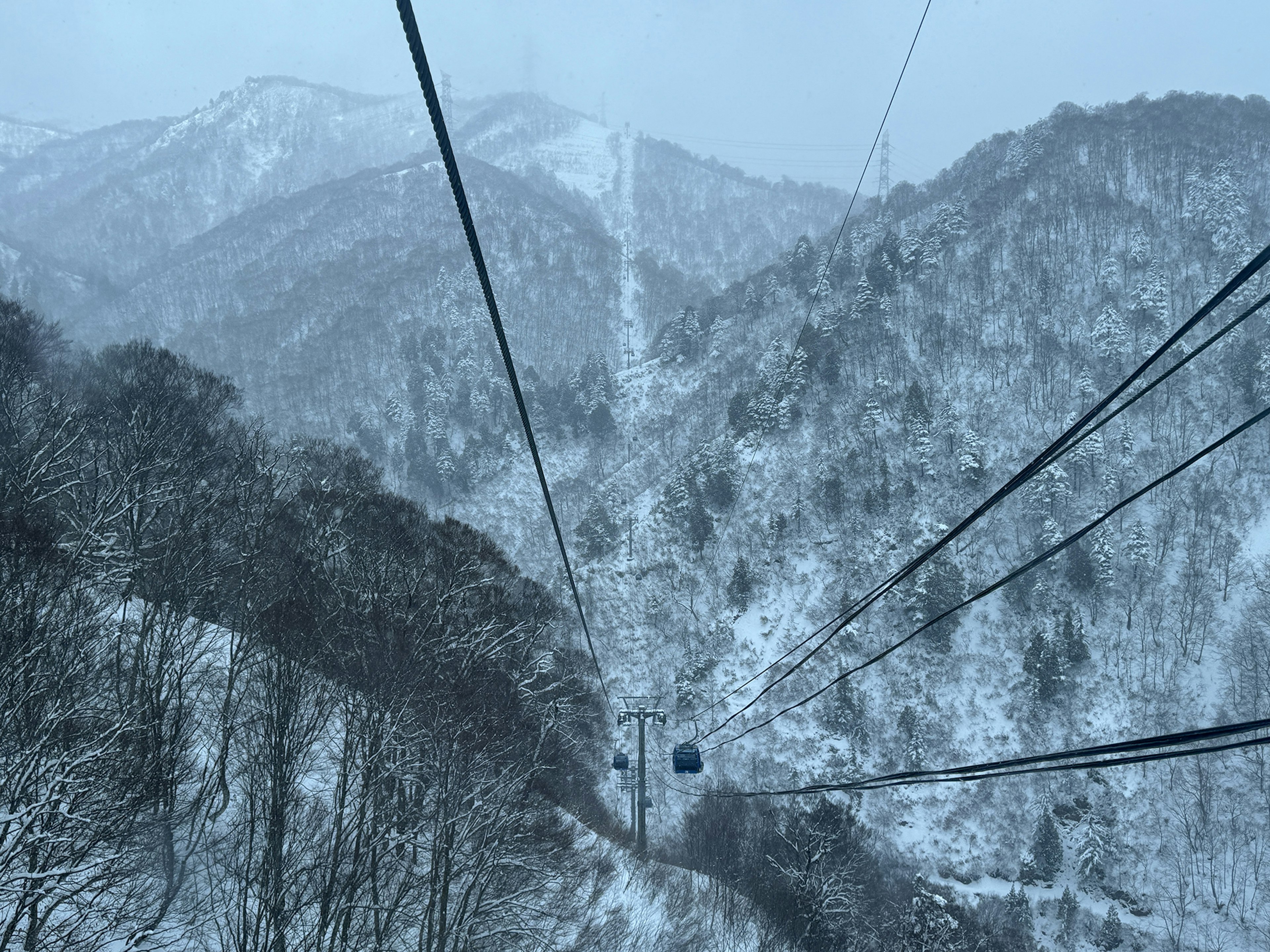 Vue d'un téléphérique au milieu de montagnes enneigées