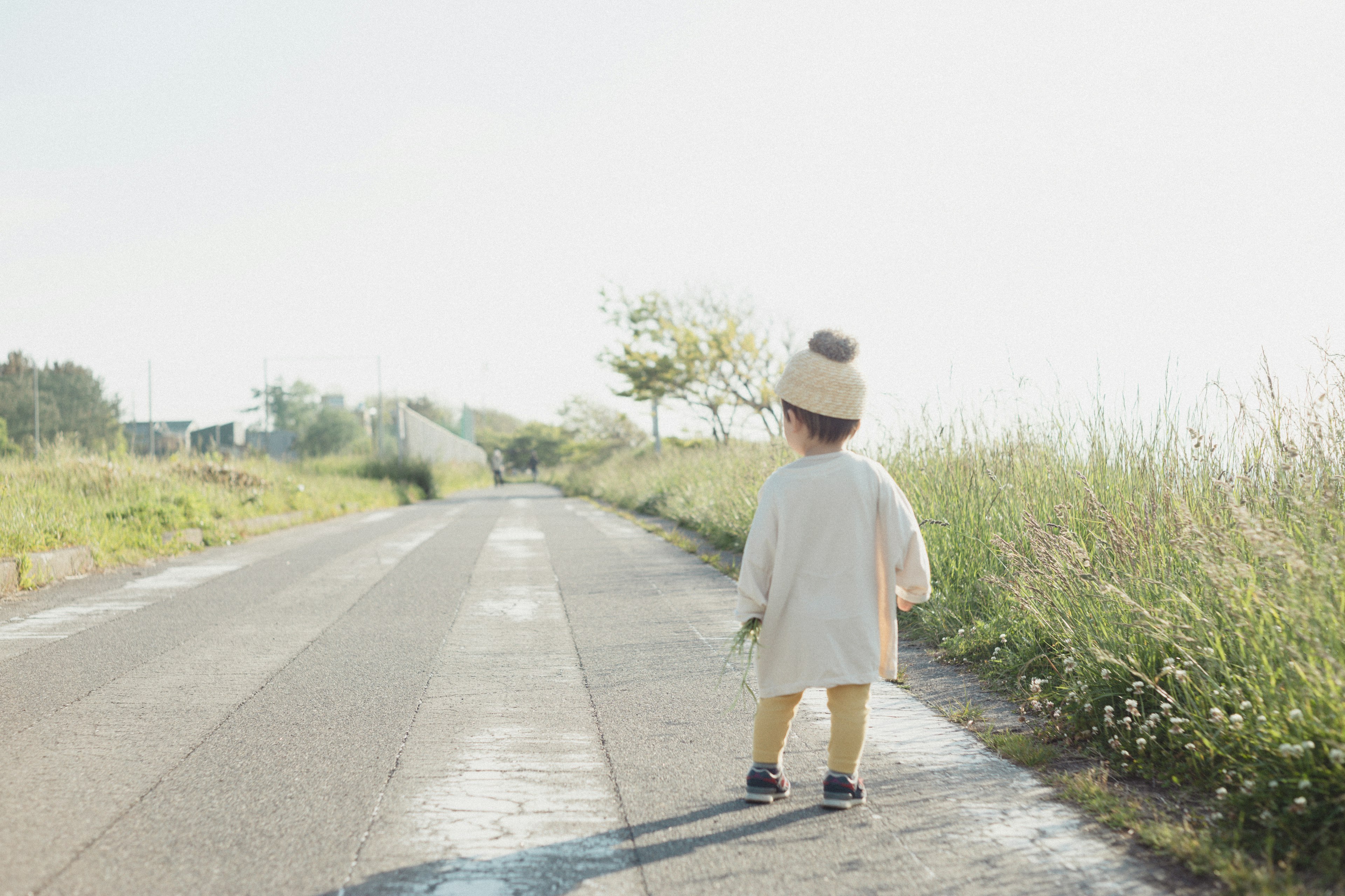 Bambino che cammina su una strada tranquilla circondata da vegetazione