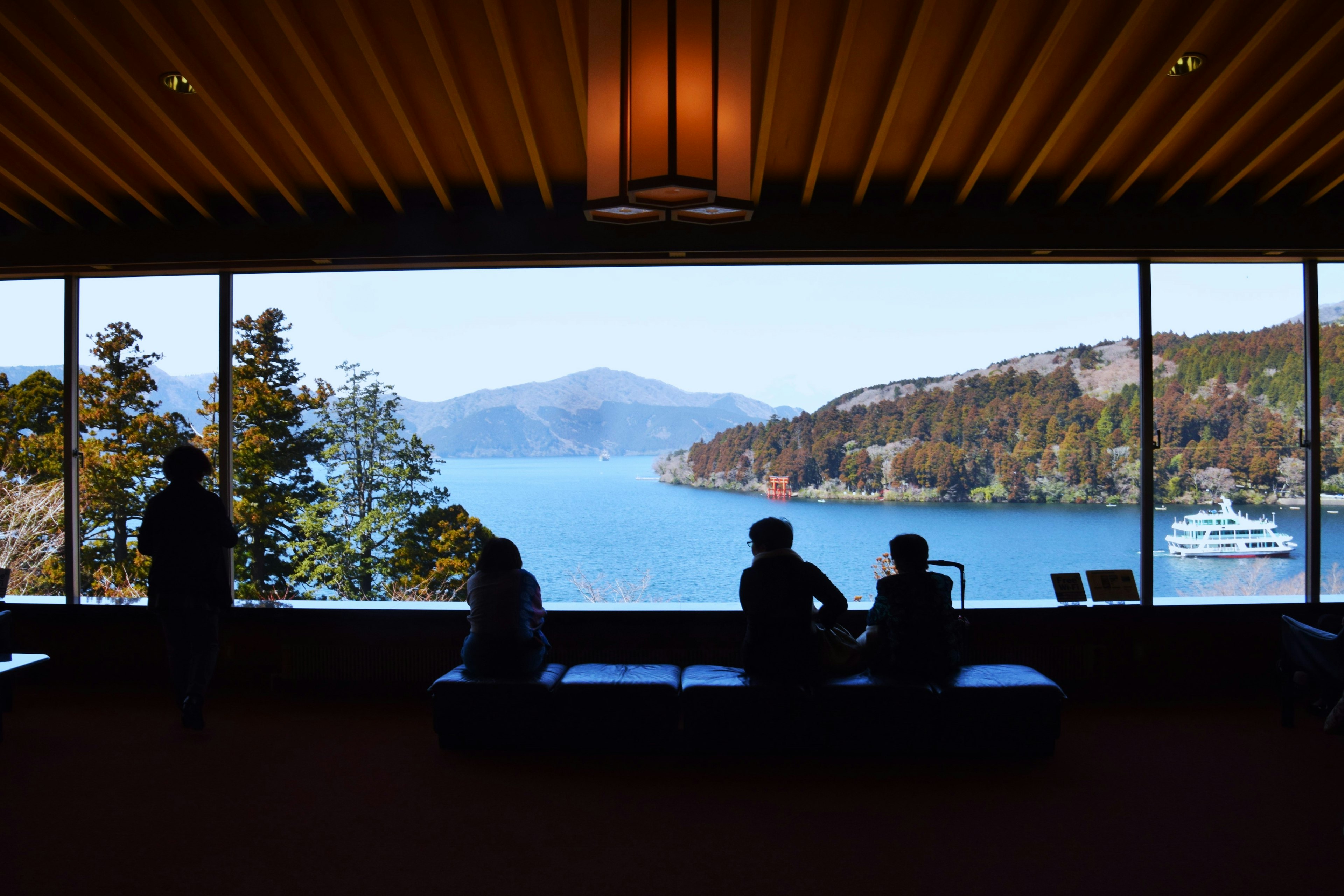 Malersicher Blick auf einen See und Berge mit Silhouetten von Menschen am Fenster