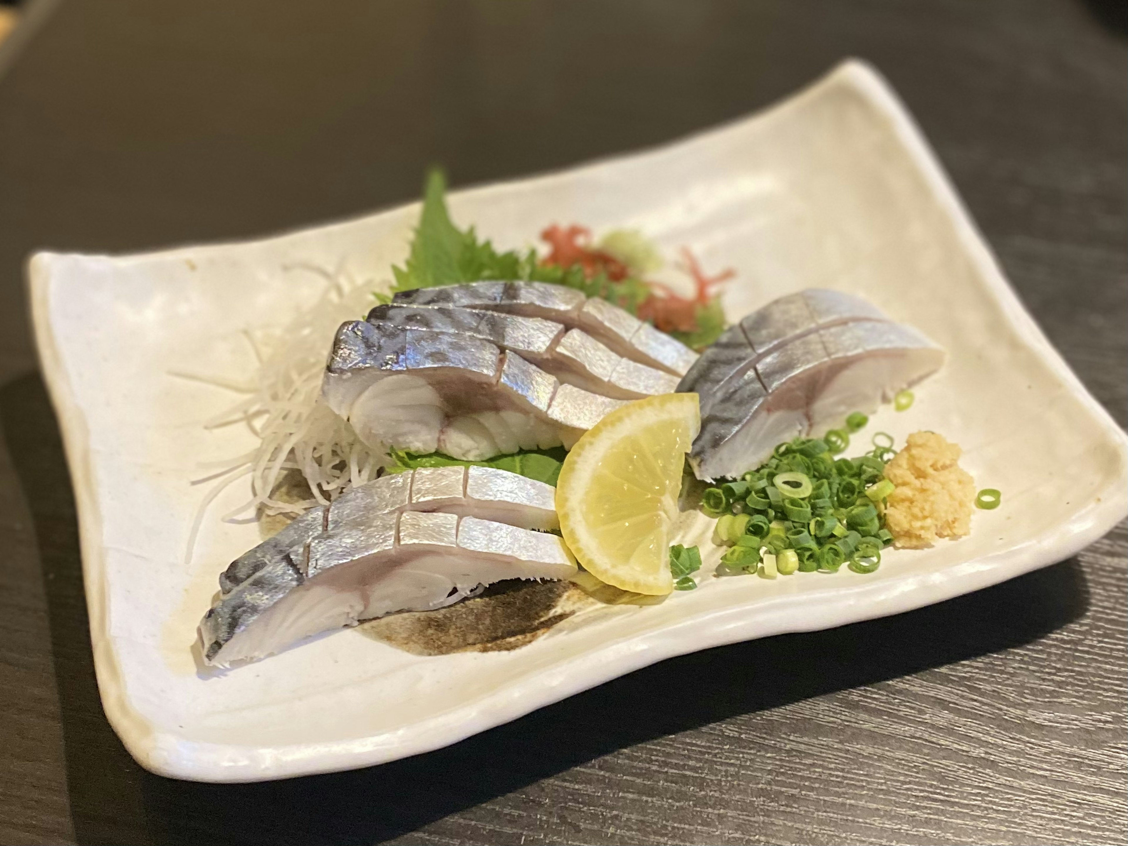 Frischer Sashimi-Teller mit Fischscheiben, garniert mit Zitrone und Gemüse