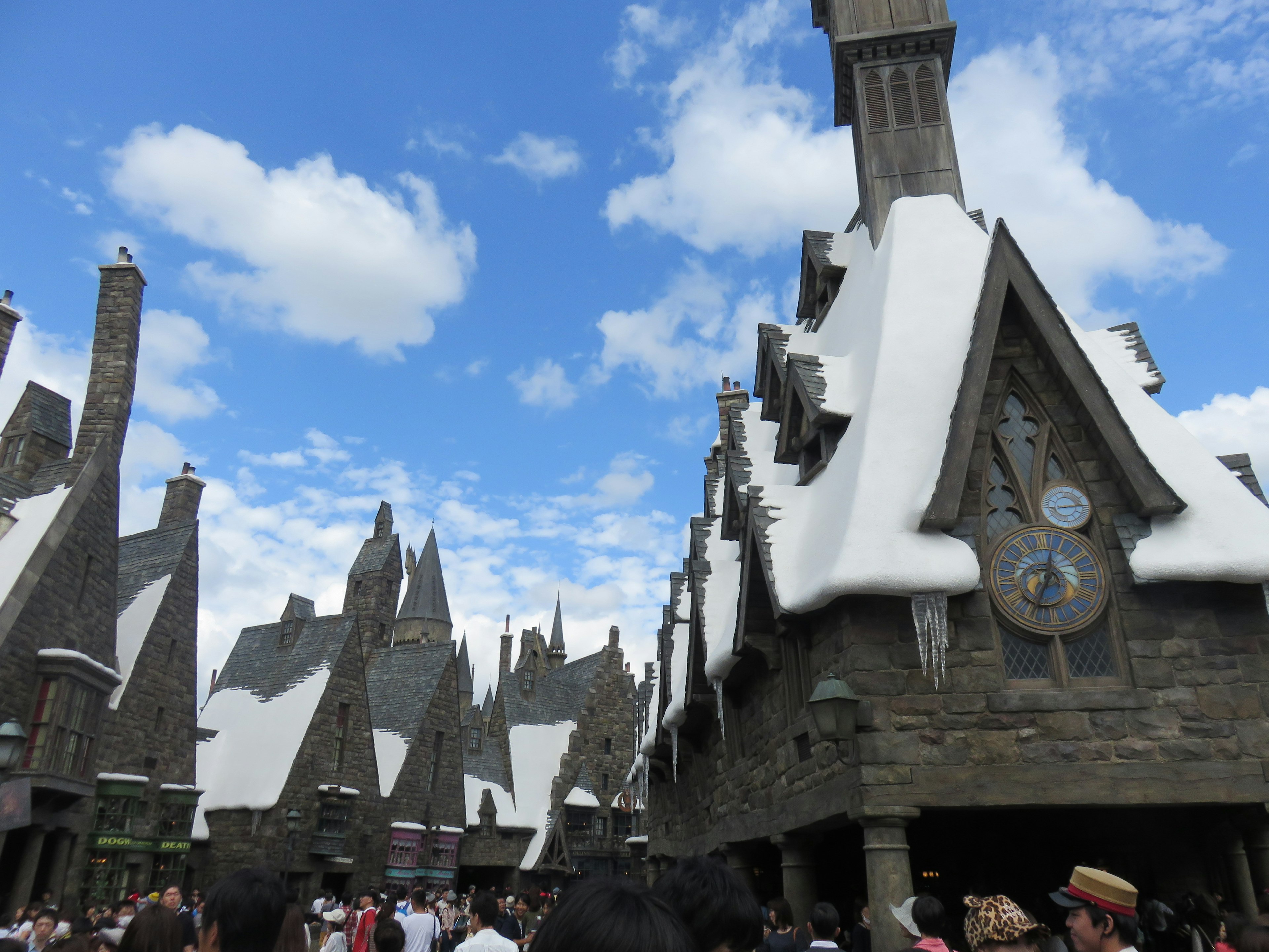 Snow-covered rooftops in a magical village under a blue sky with people