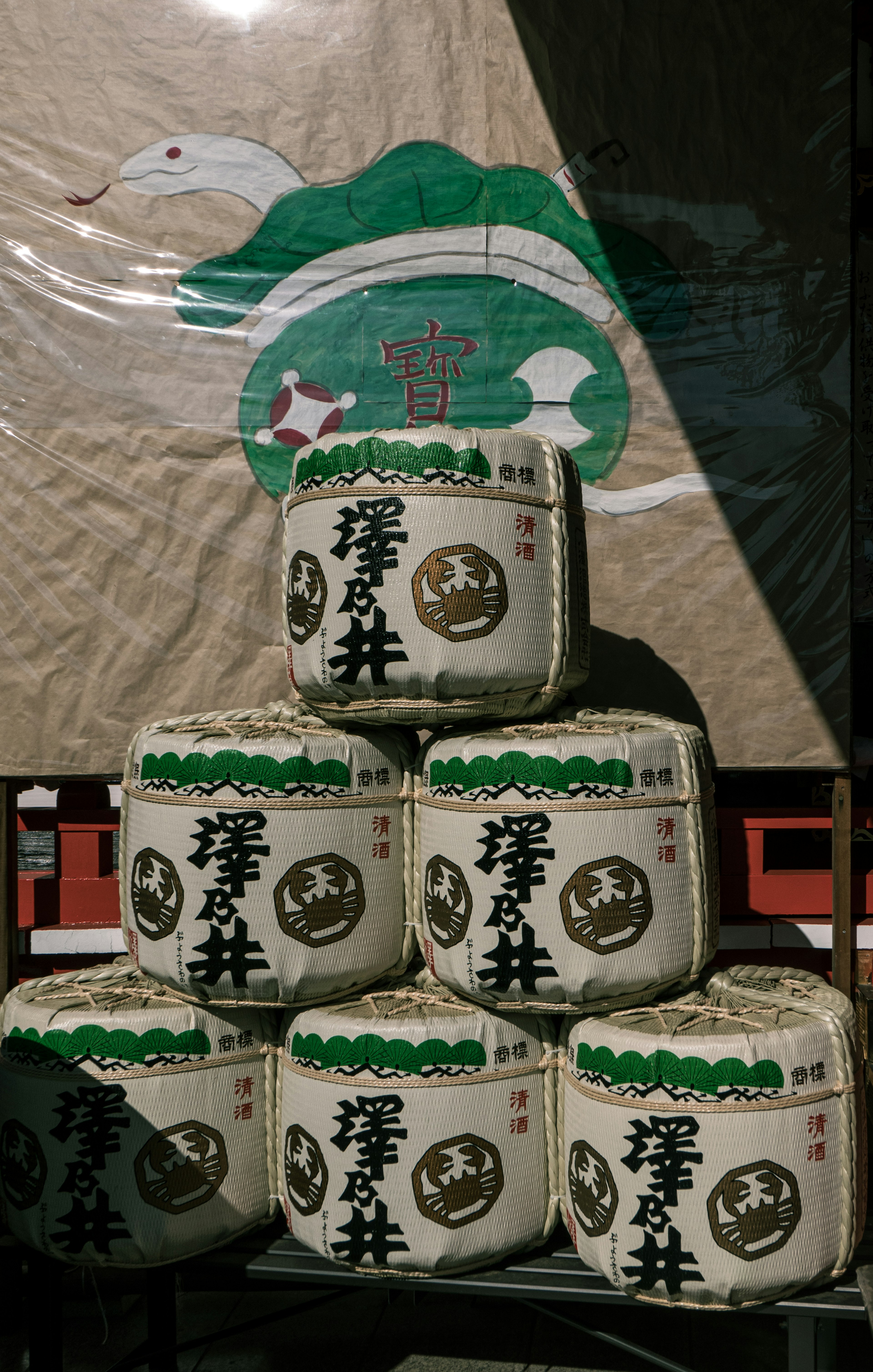 Stacked sake barrels with a turtle design in the background