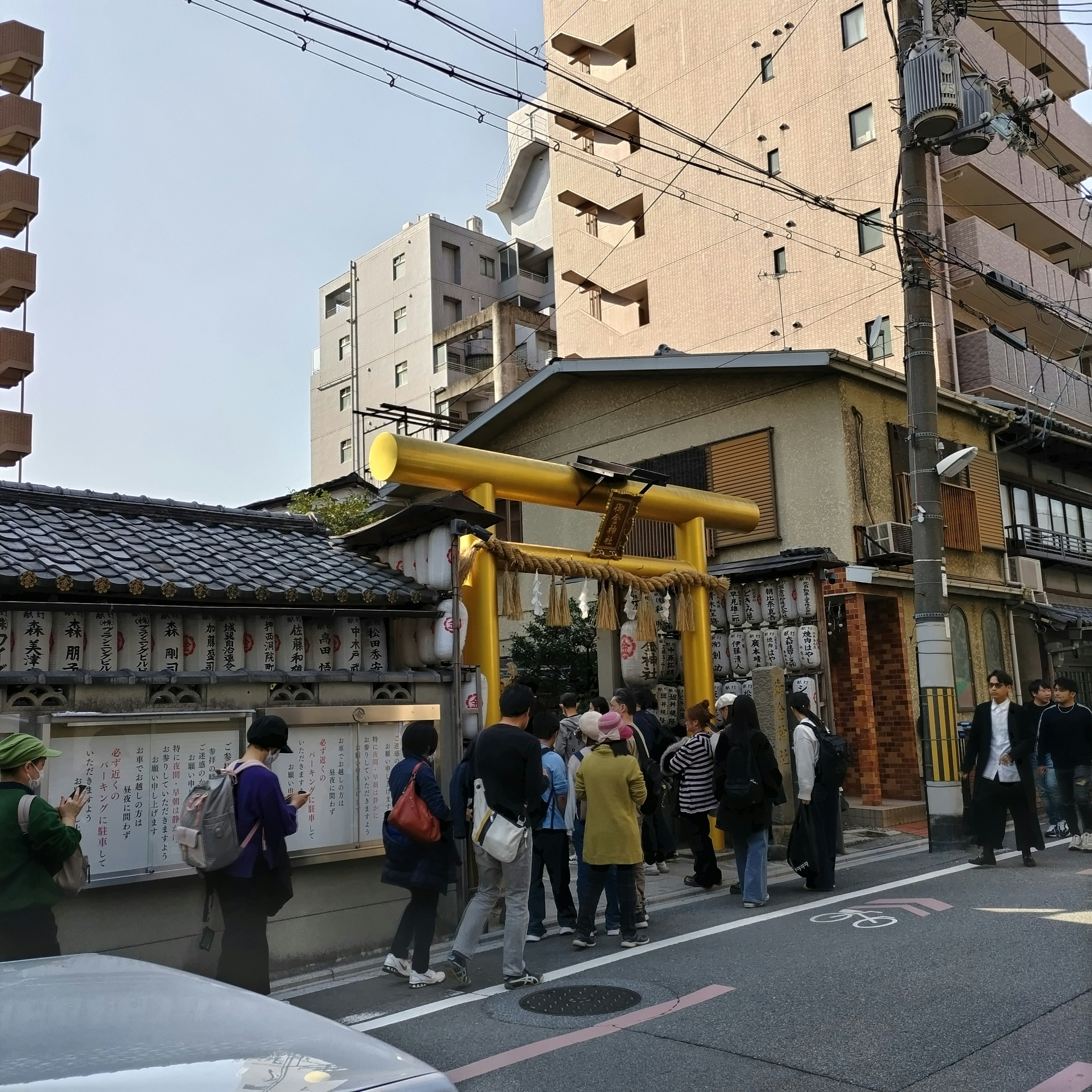 Street view featuring a yellow torii gate with a crowd of people