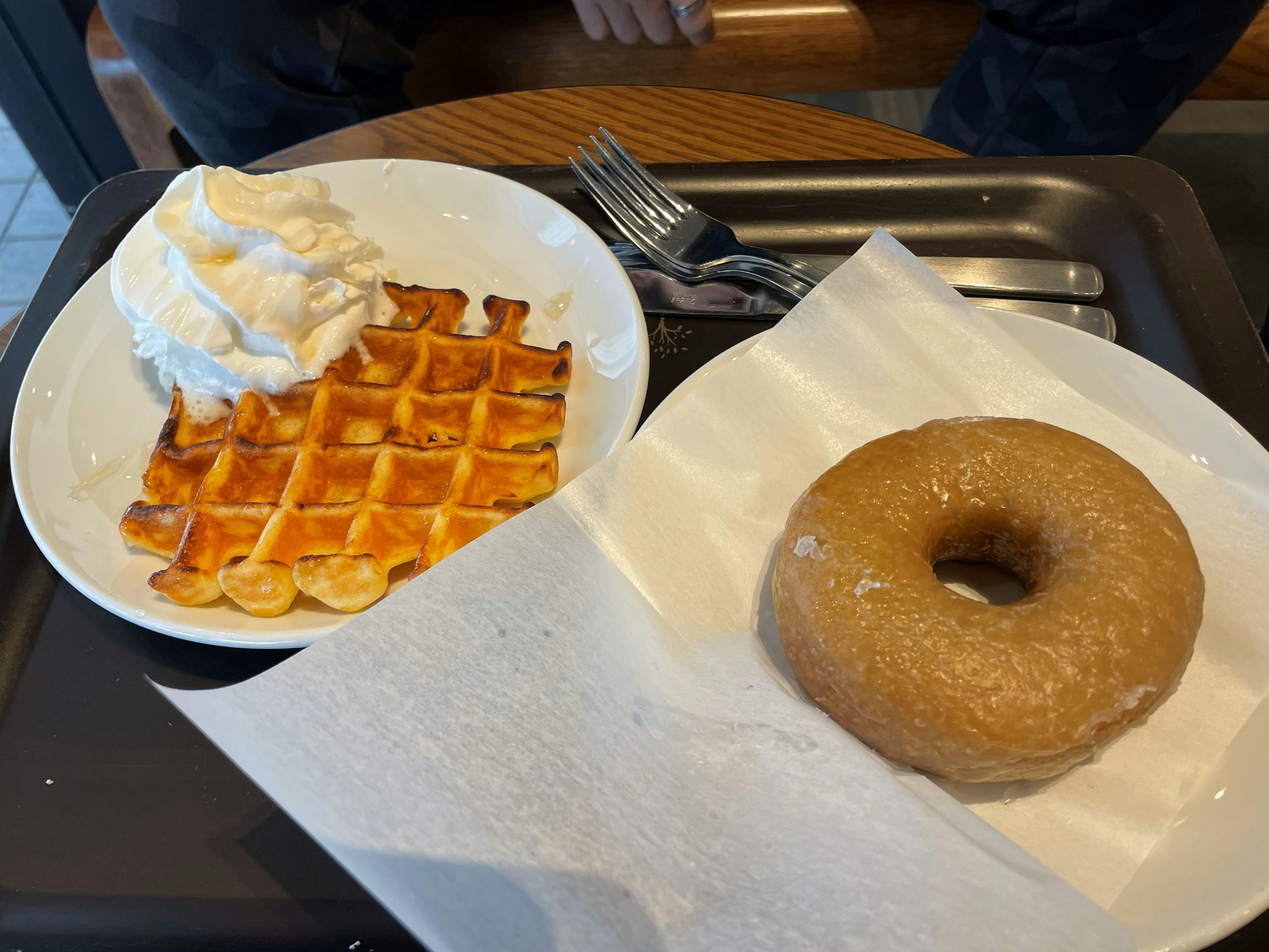 Un delicioso postre con un waffle cubierto de crema batida y una dona glaseada en un plato