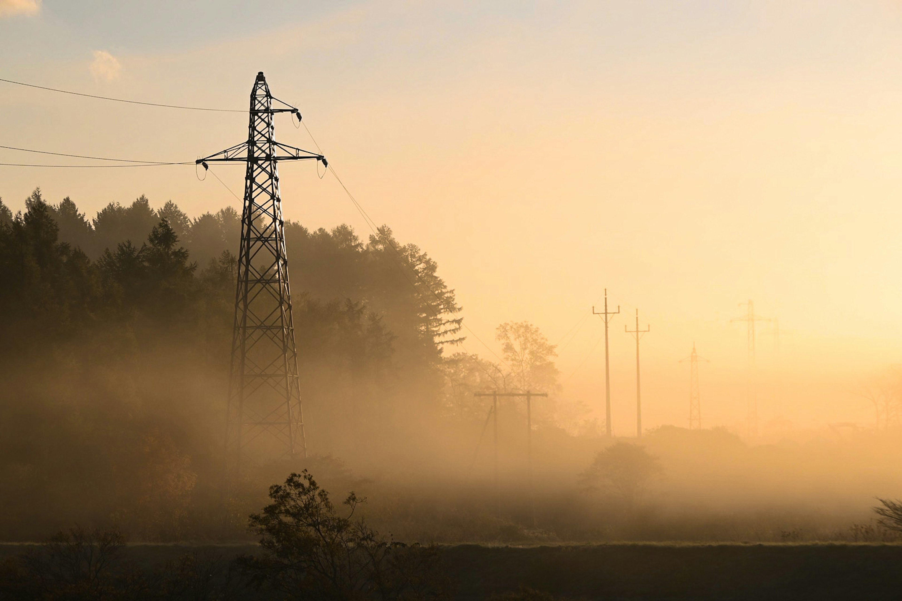 High voltage power lines in fog with a soft sunset