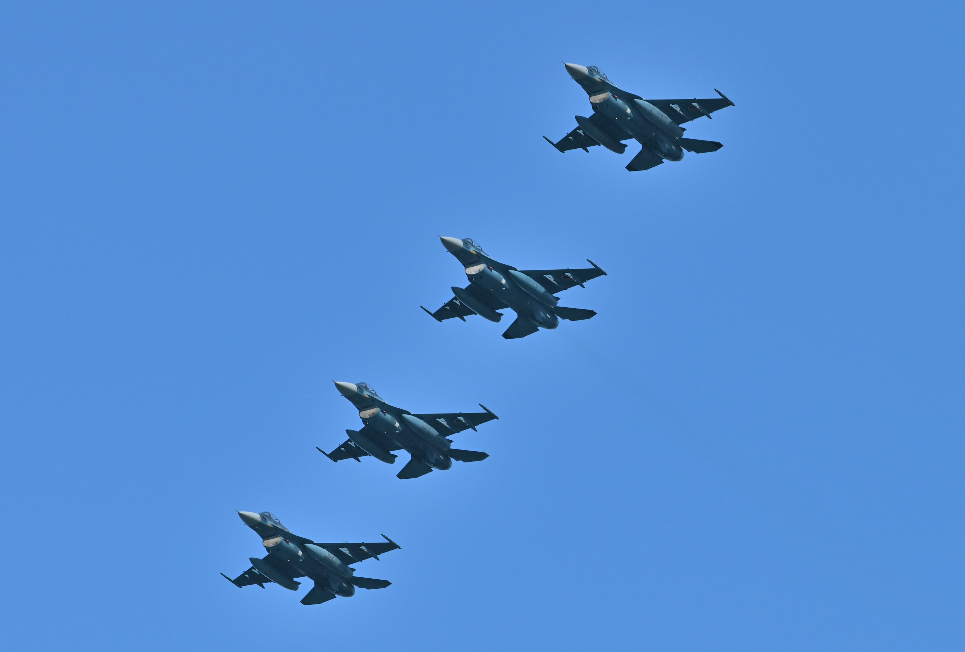 Formación de cuatro aviones de combate volando en un cielo azul