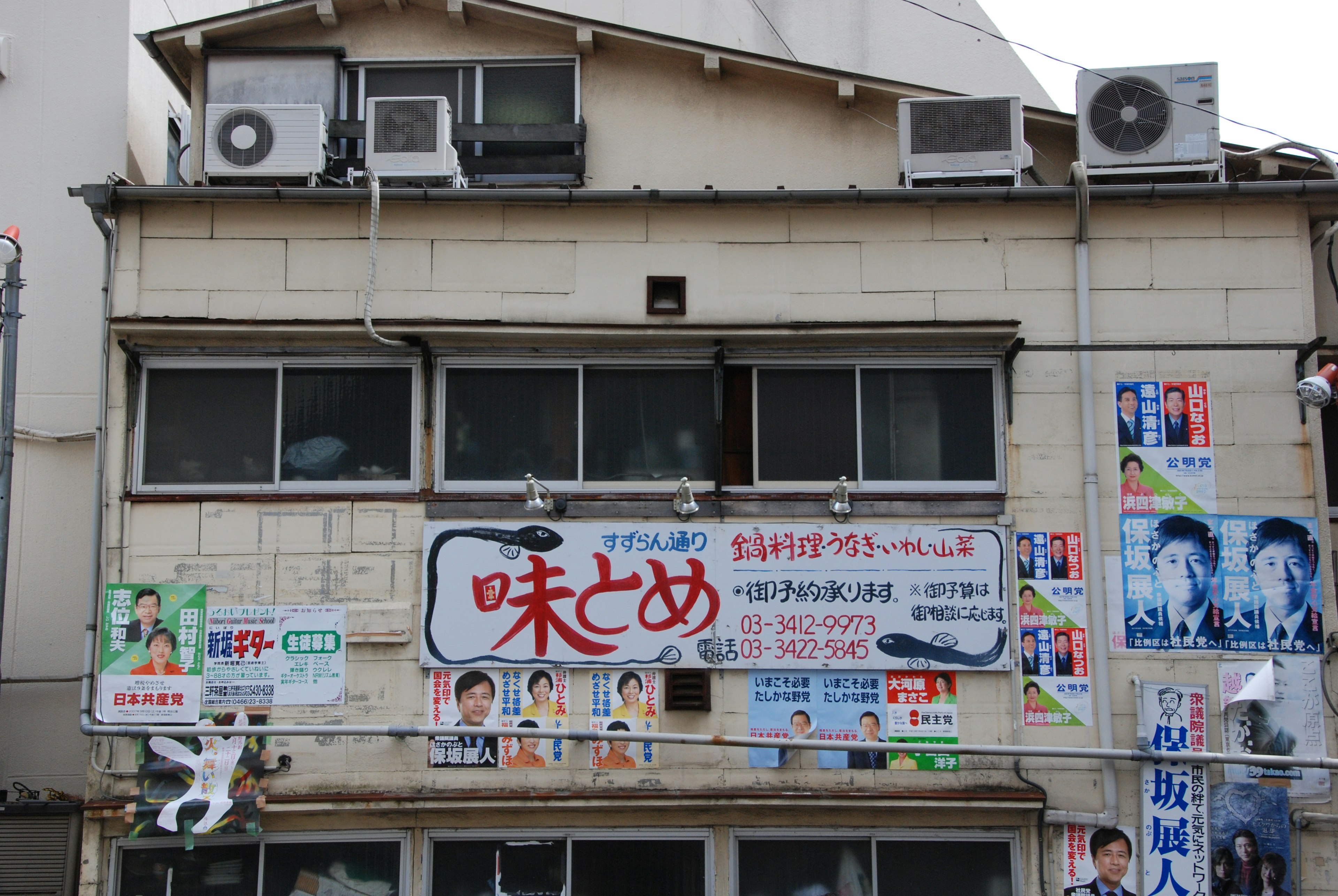 Exterior of an old building featuring a large sign and various posters