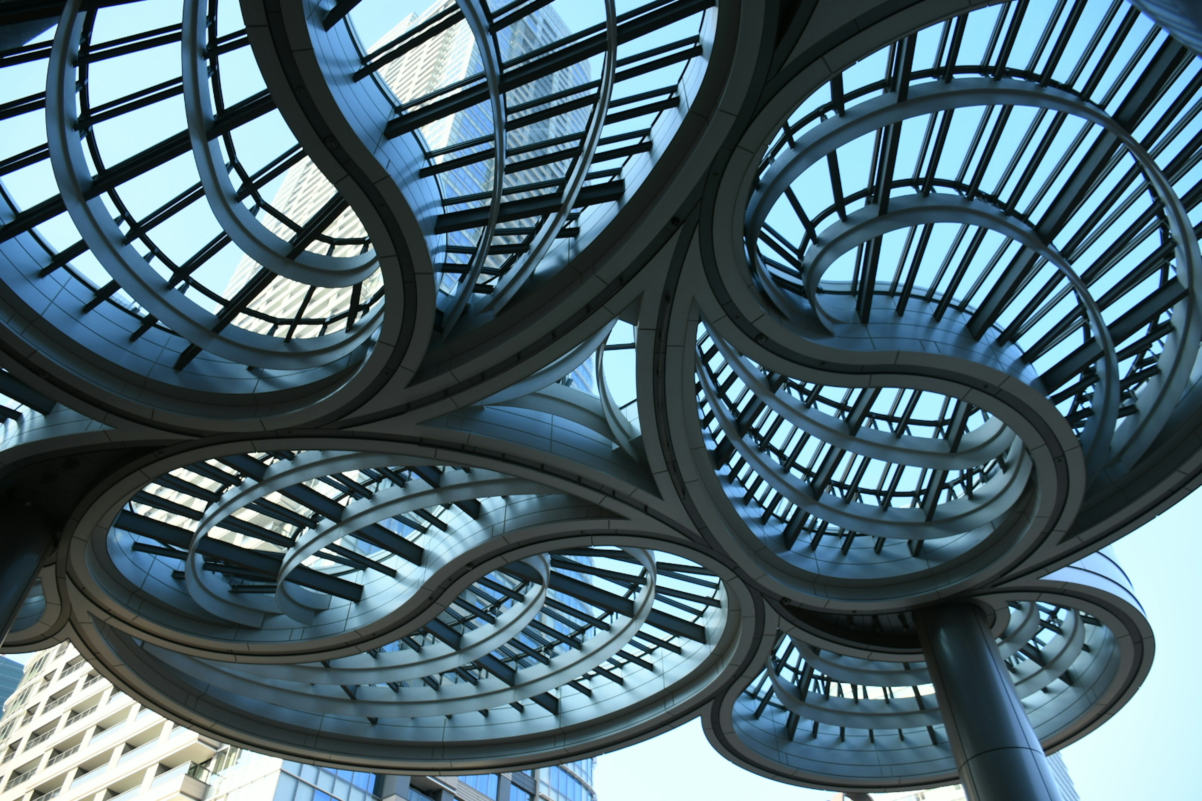 Complex metal structure viewed from below with blue sky