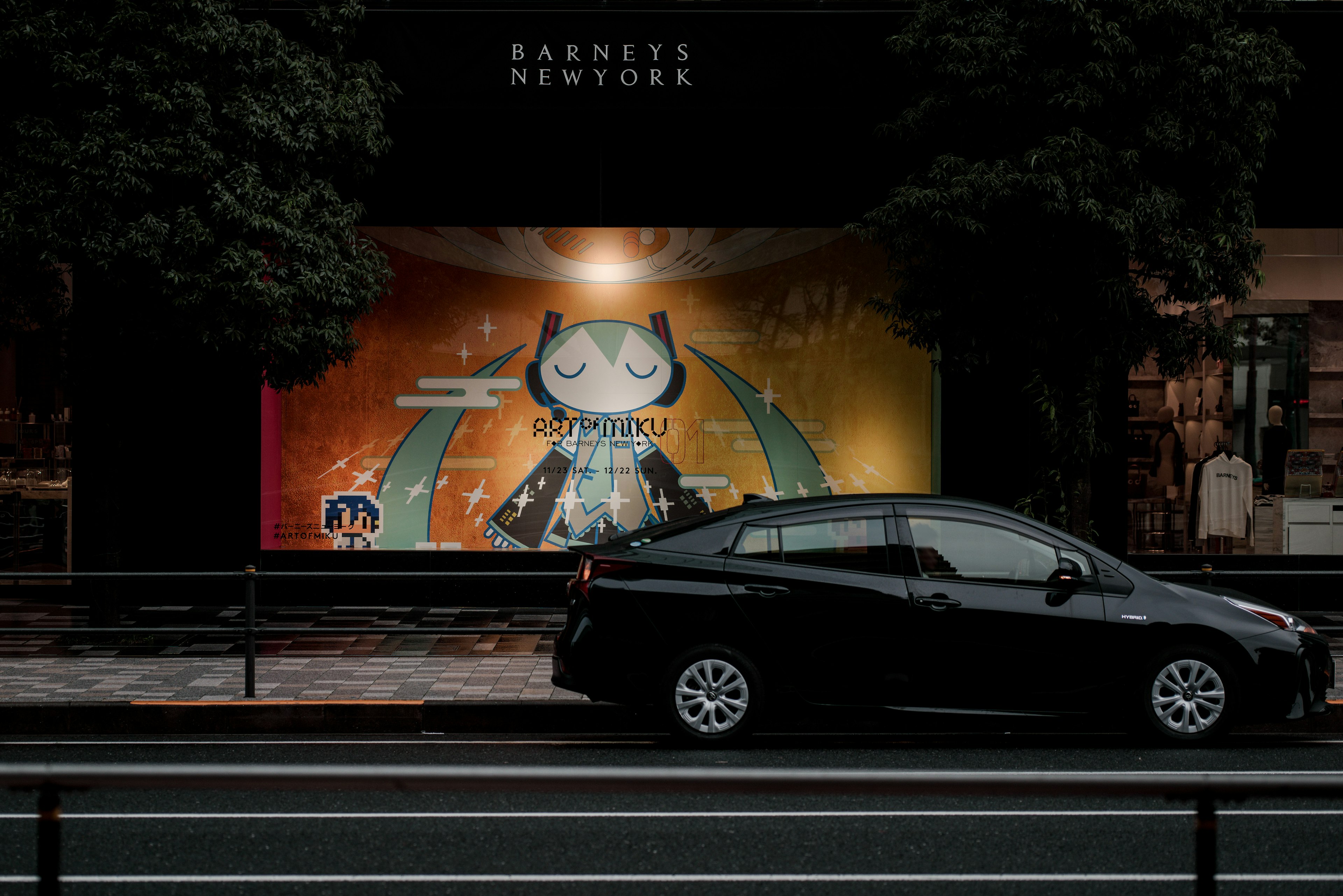 Colorful mural with a character next to a black car on a city street