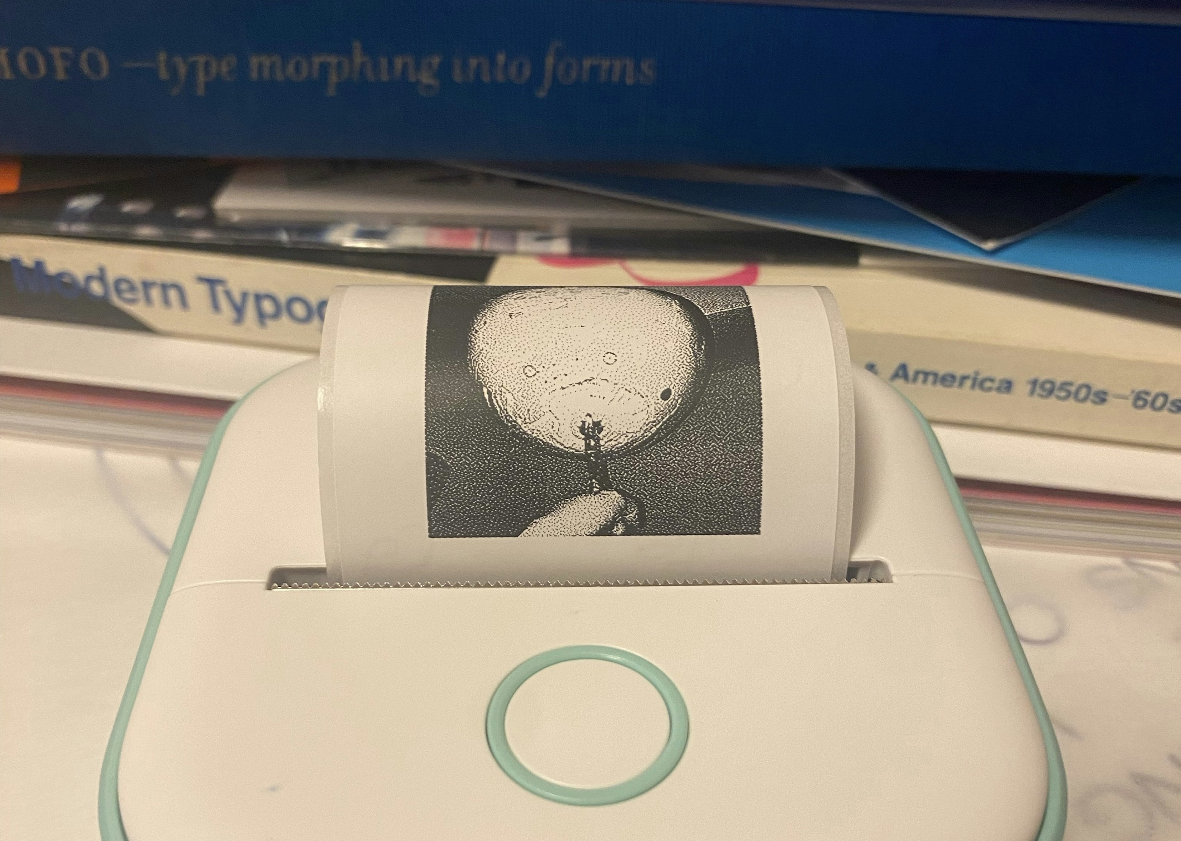 Image of a hand holding a printed white balloon with books in the background