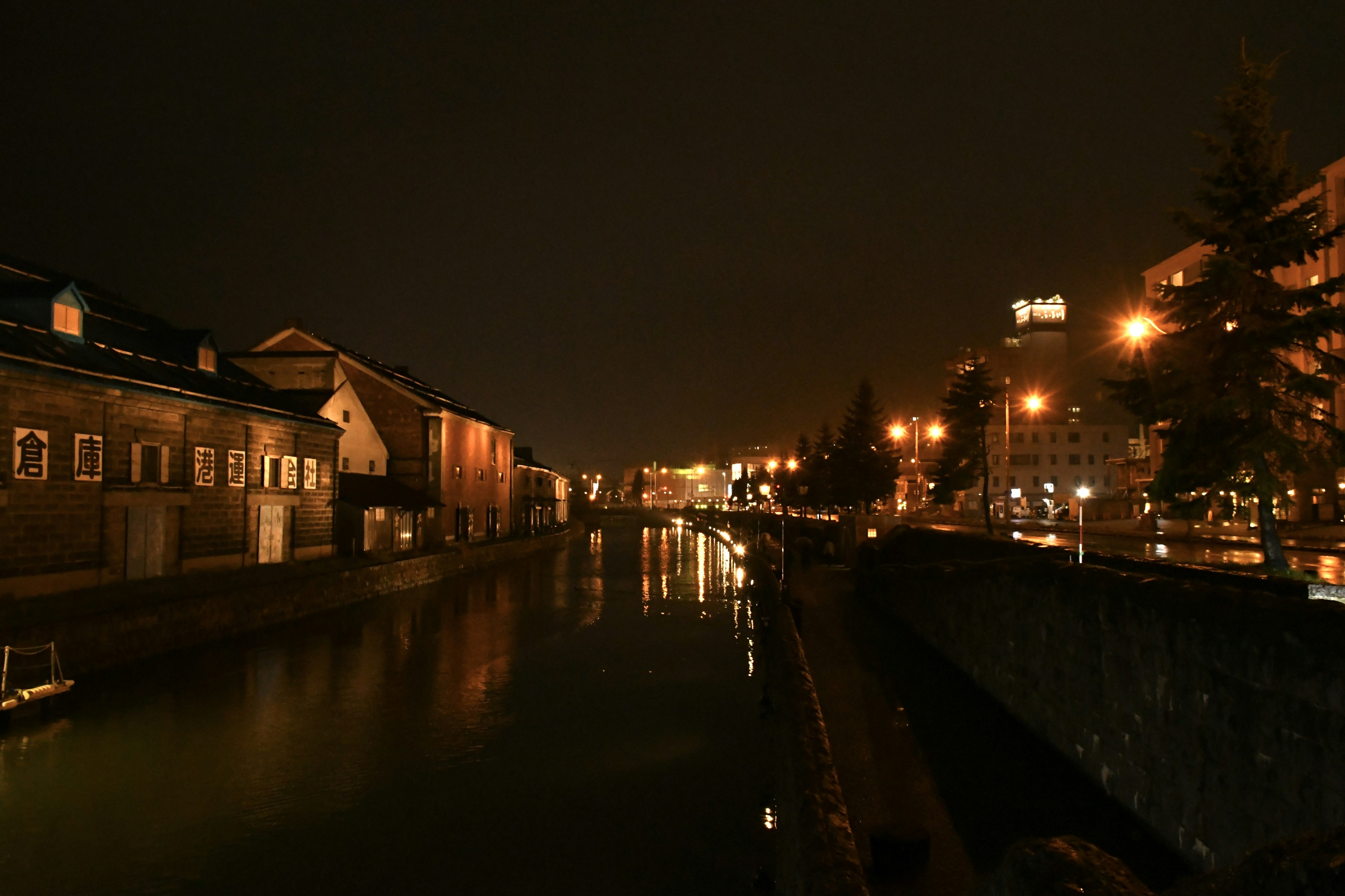 Pemandangan malam kanal dengan bangunan yang diterangi dan lampu jalan