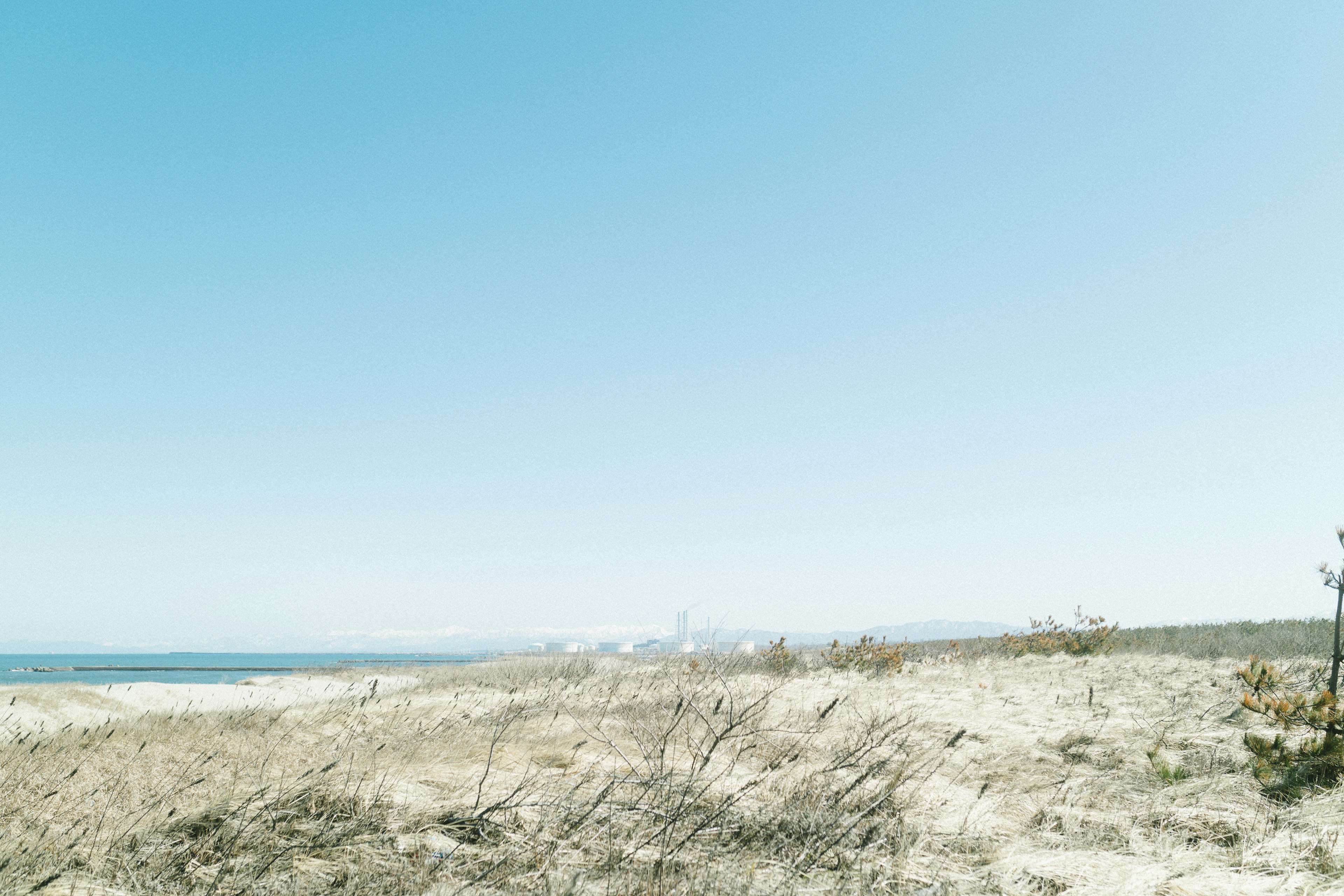 Landscape of sand dunes with a blue sky and ocean view