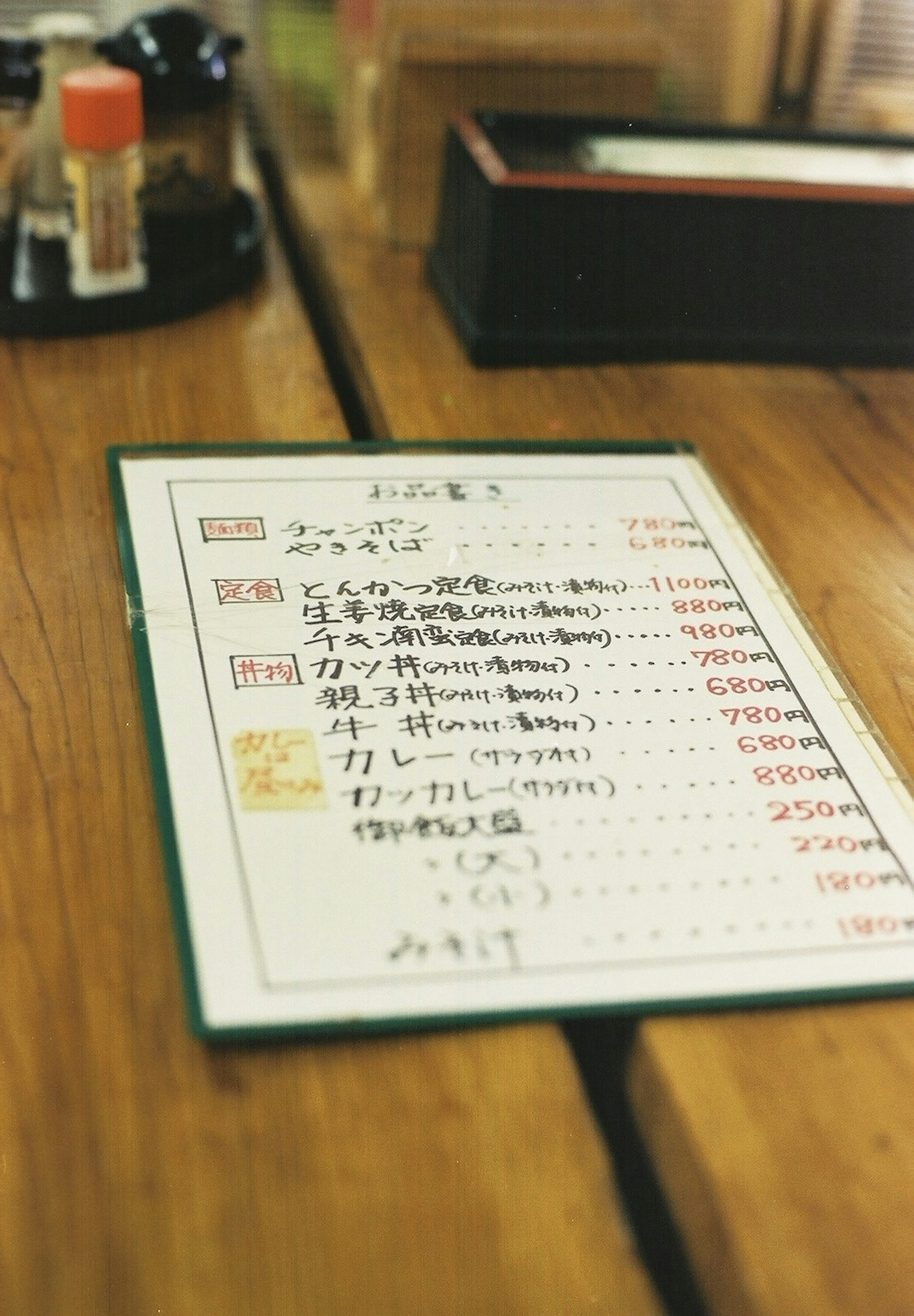 Foto de un menú colocado sobre una mesa con platos y precios escritos en japonés