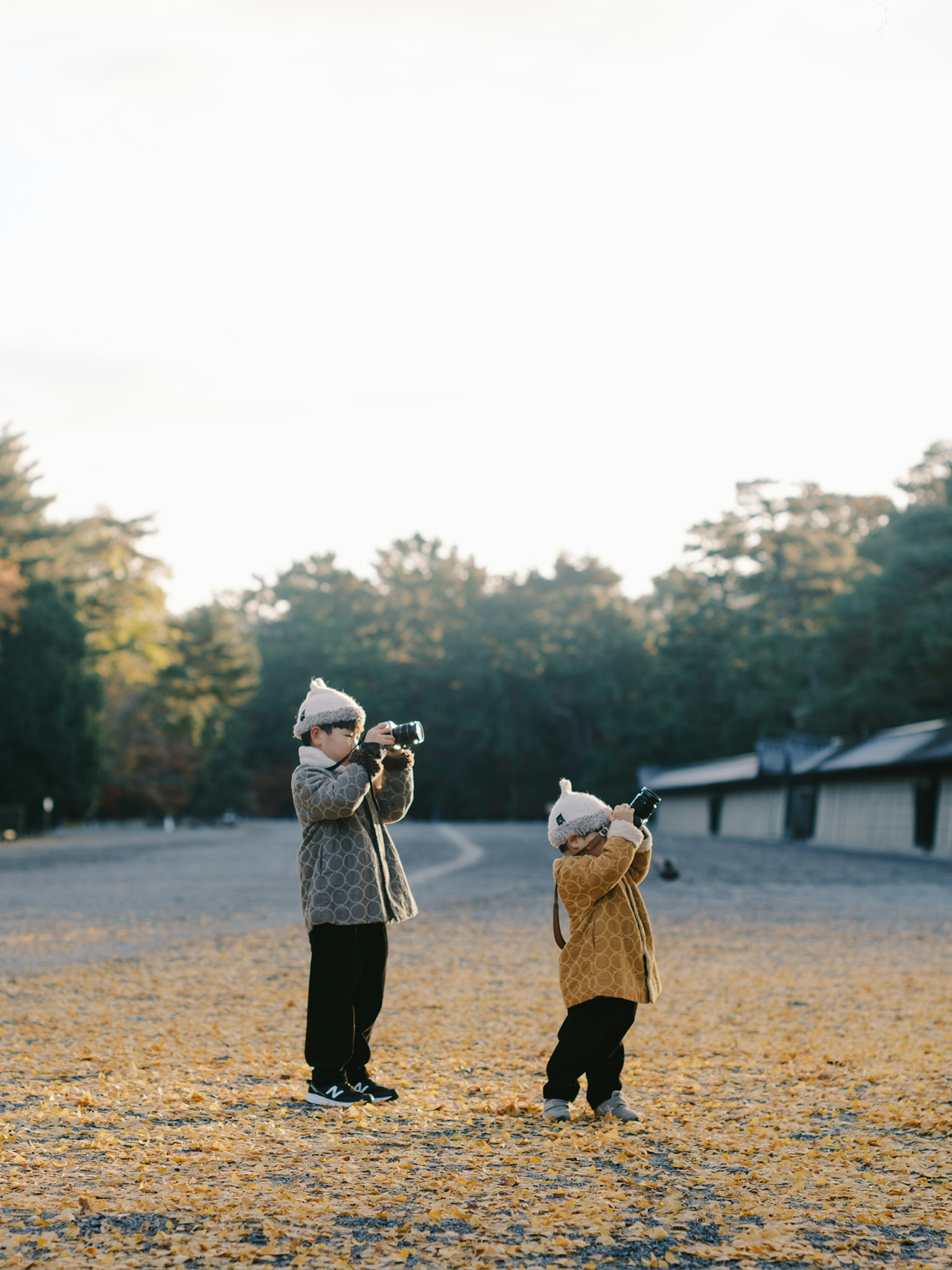 Zwei Kinder mit Kameras, die draußen Fotos machen