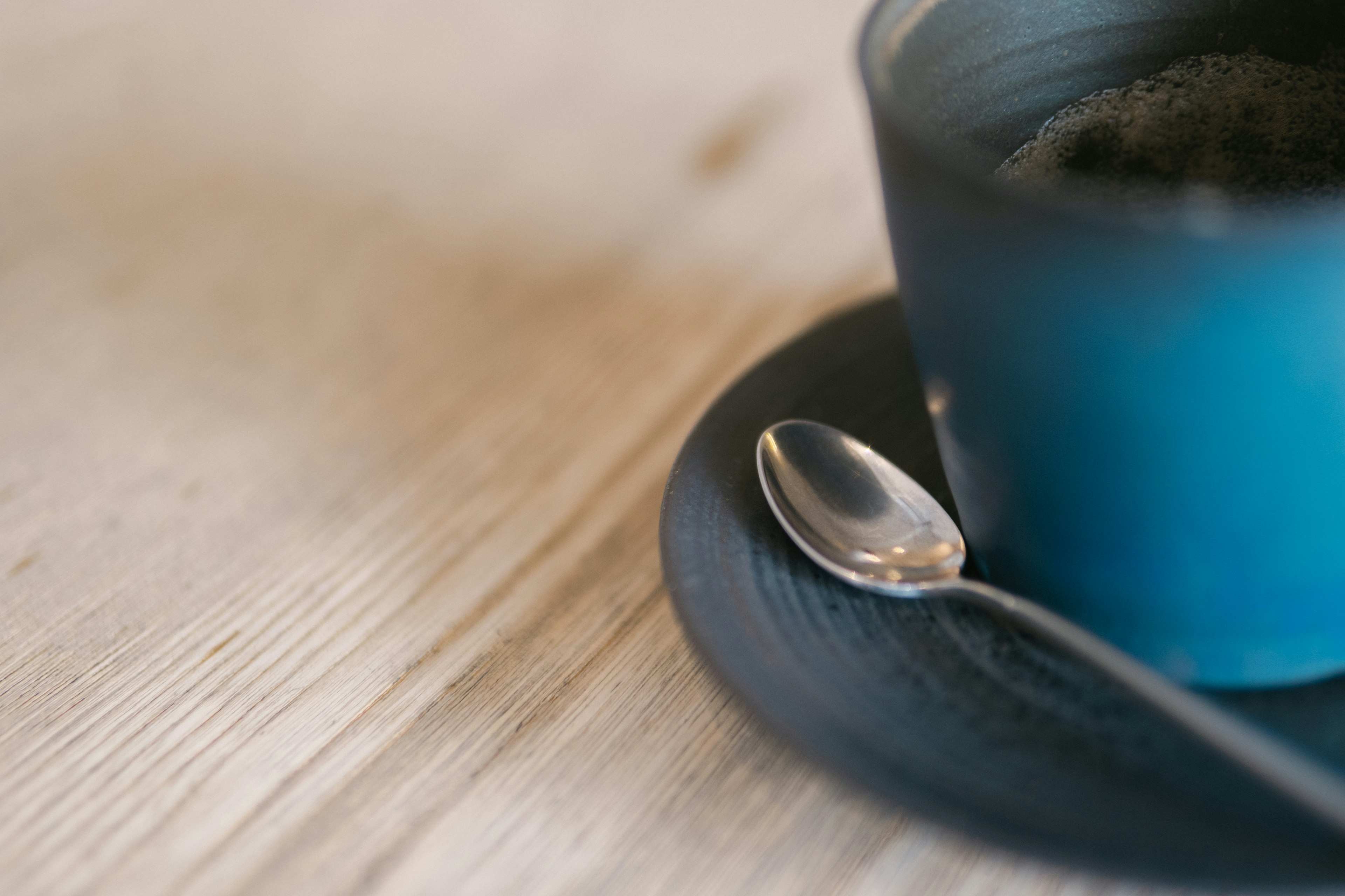 Eine blaue Tasse mit einem kleinen Löffel auf einem Holztisch