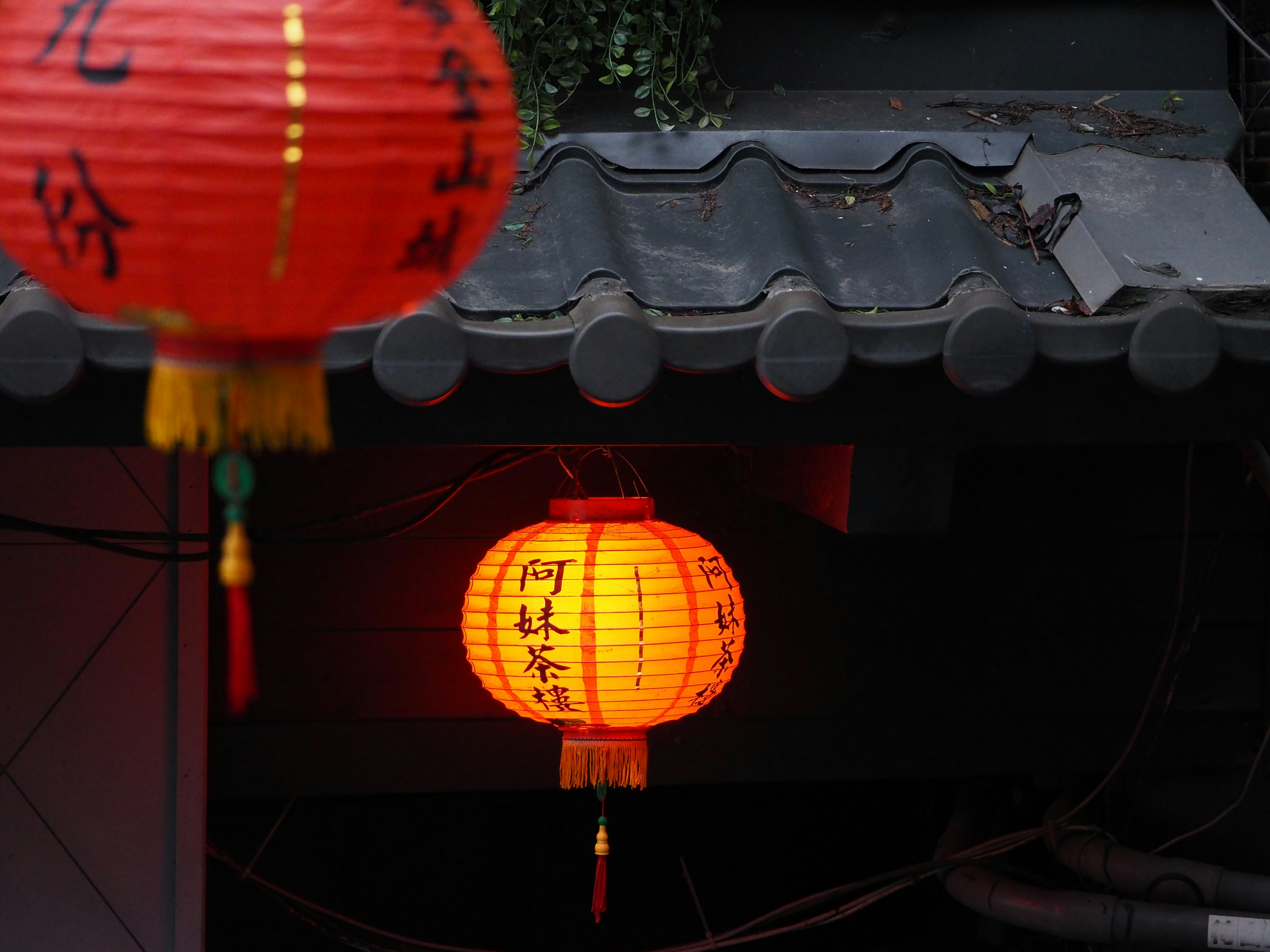 Red lanterns hanging above a traditional roof in a nighttime setting