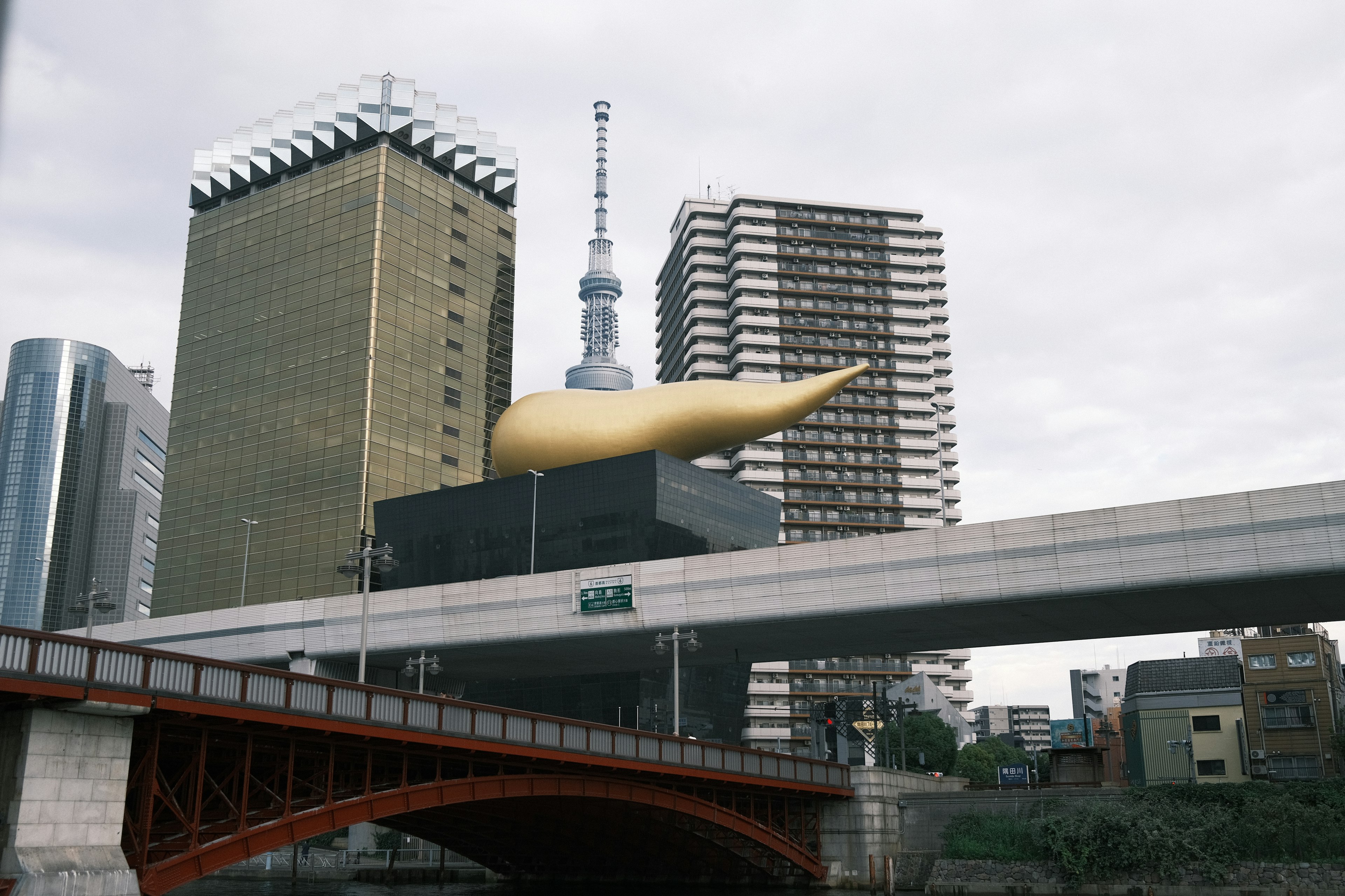 Goldene flammenförmige Skulptur auf einer Brücke über den Sumida-Fluss mit umliegenden Gebäuden