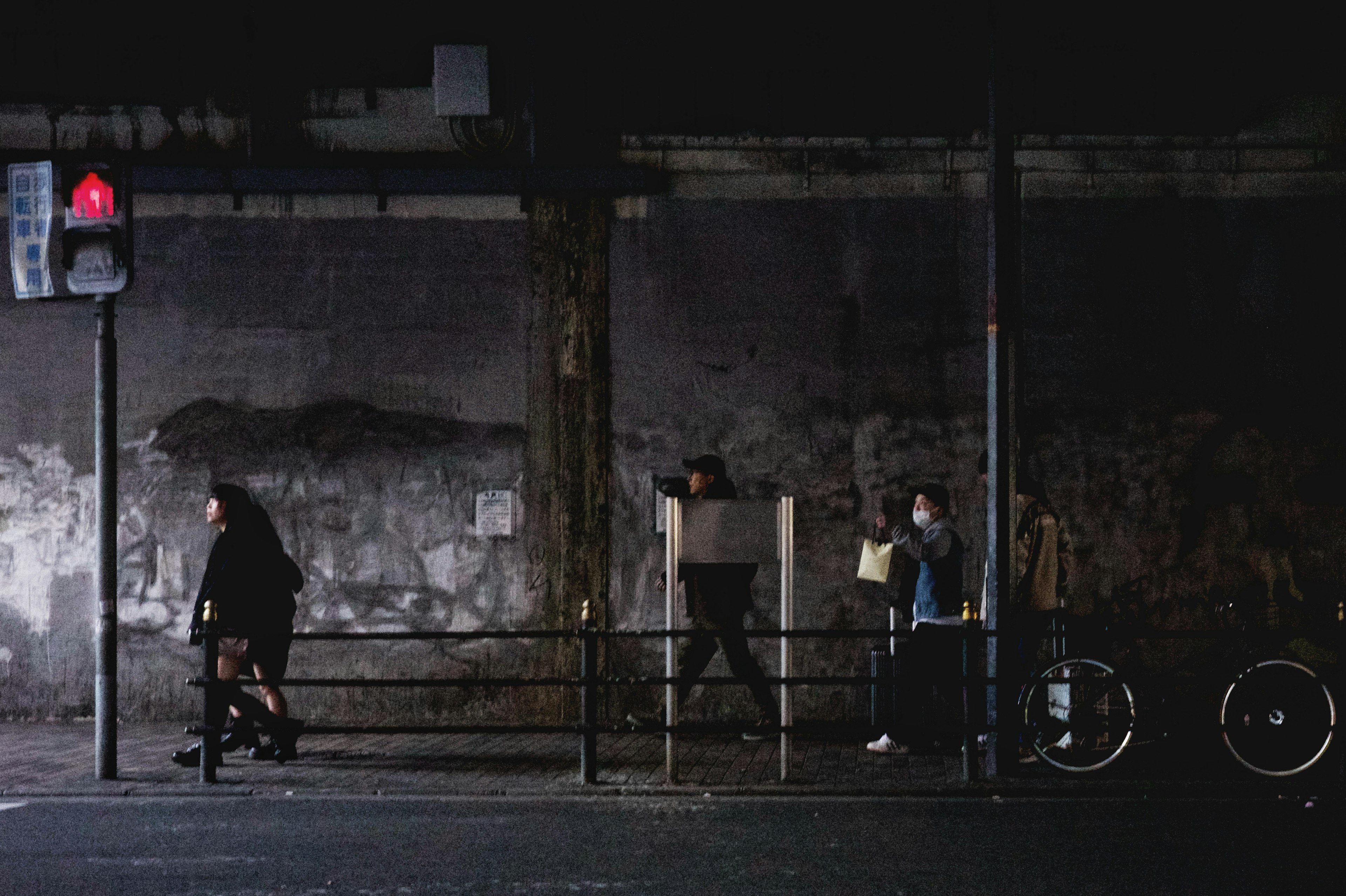 People waiting at a street corner with a traffic light and bicycles