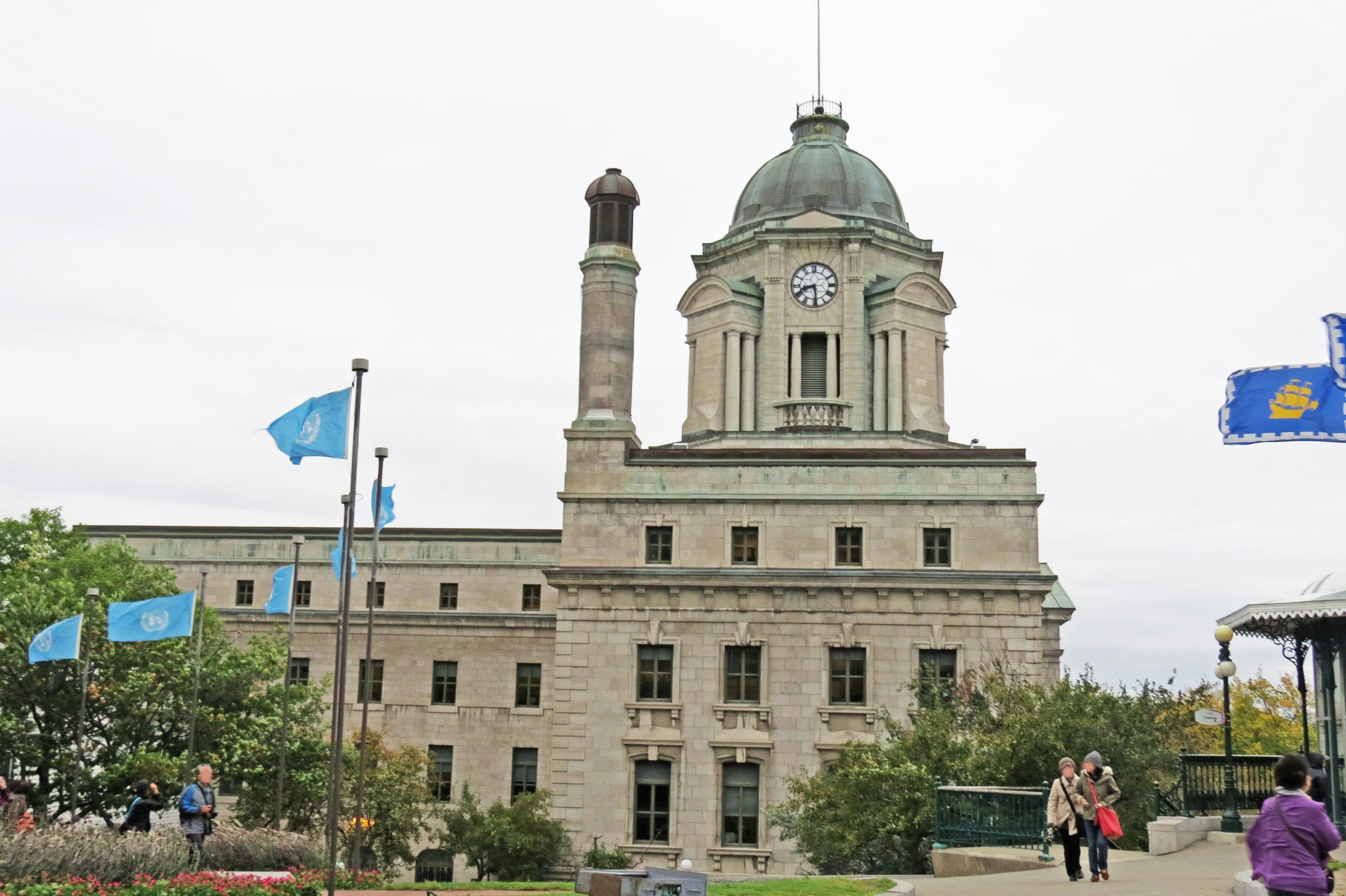 Außenansicht eines historischen Gebäudes mit Uhrturm und blauen Flaggen