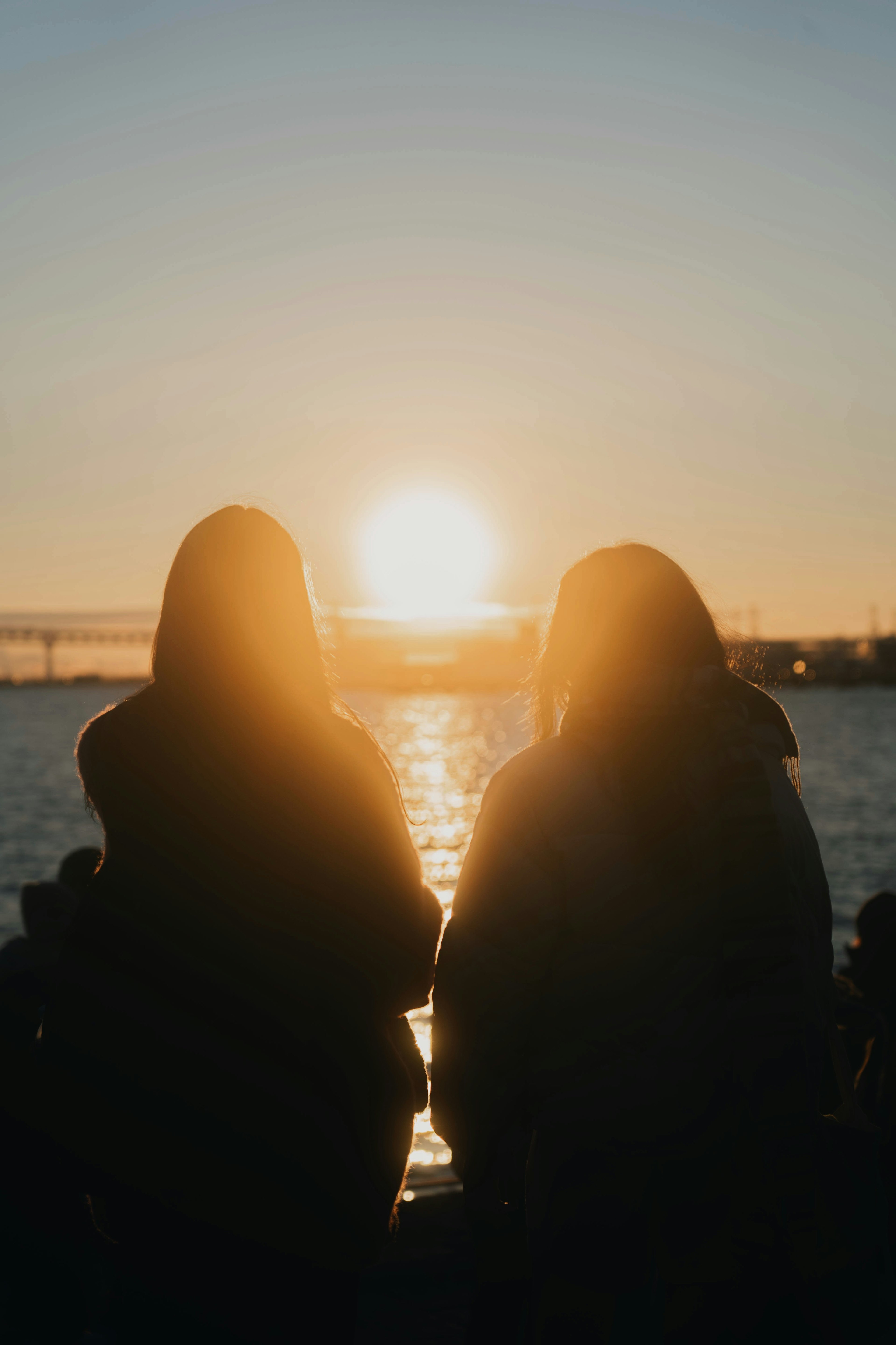 Silhouette of two women sitting with sunset in the background