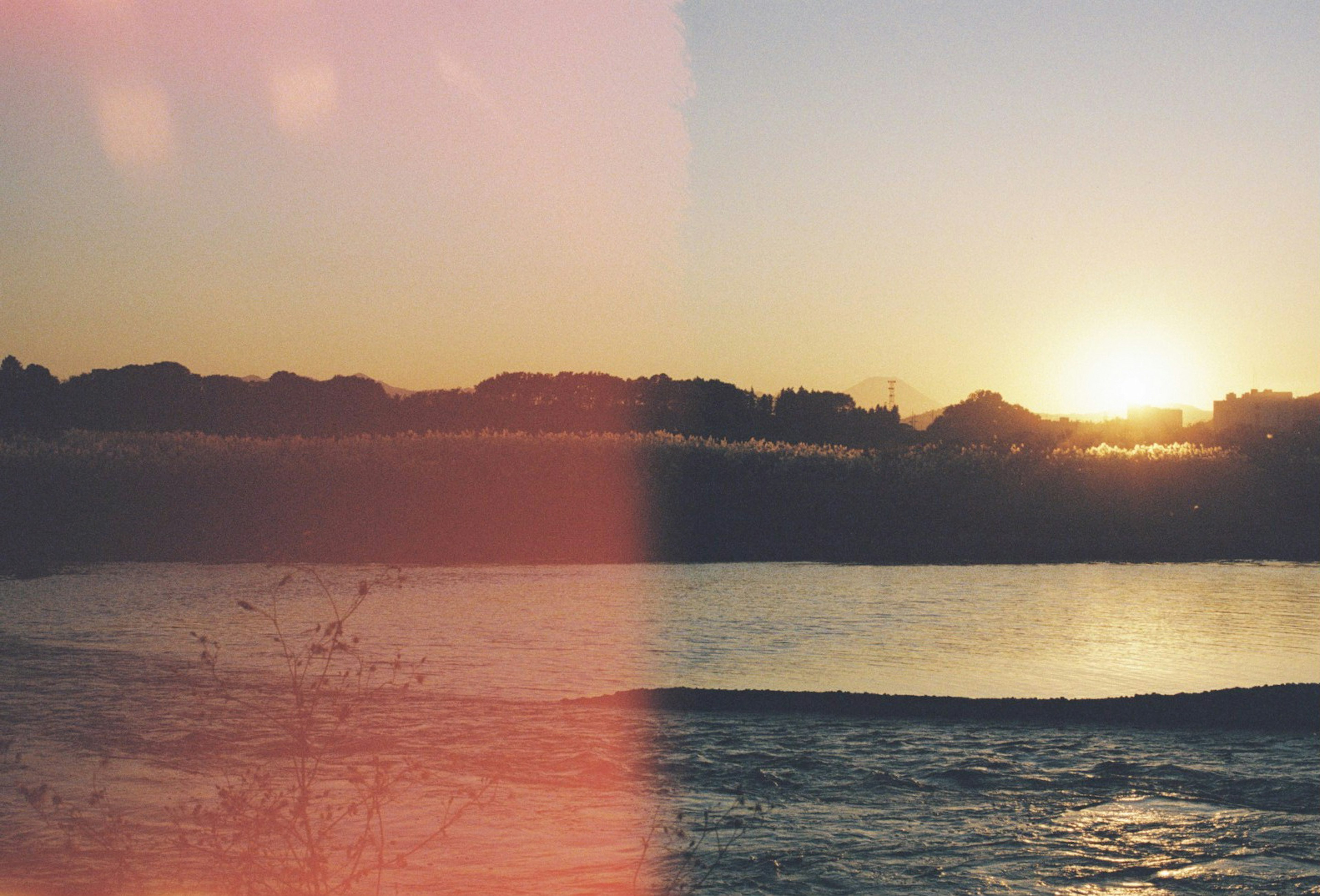 Vista panoramica di un tramonto che si riflette sull'acqua con la silhouette di un lago sereno