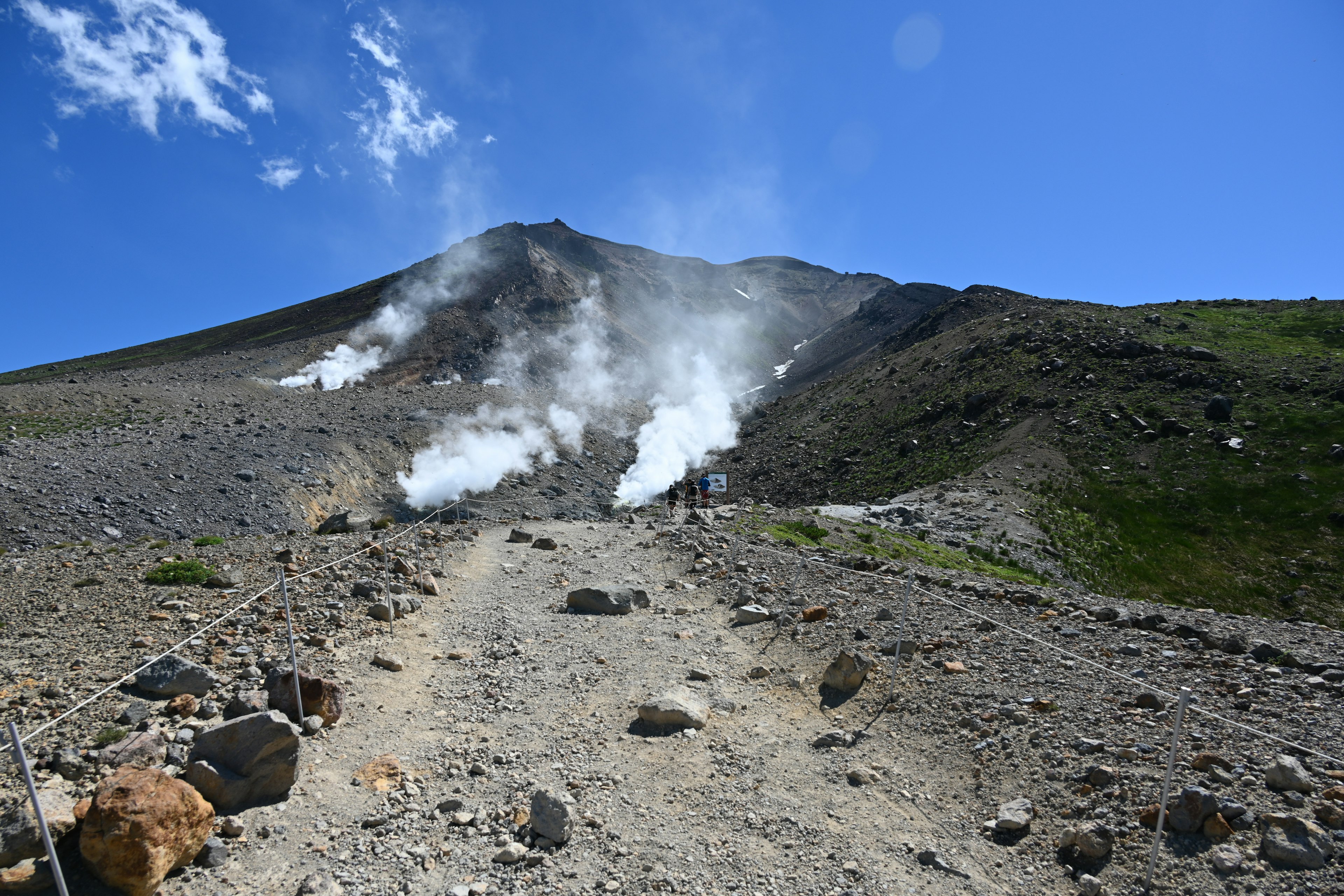 Vulkanlandschaft mit aufsteigendem Dampf und blauem Himmel