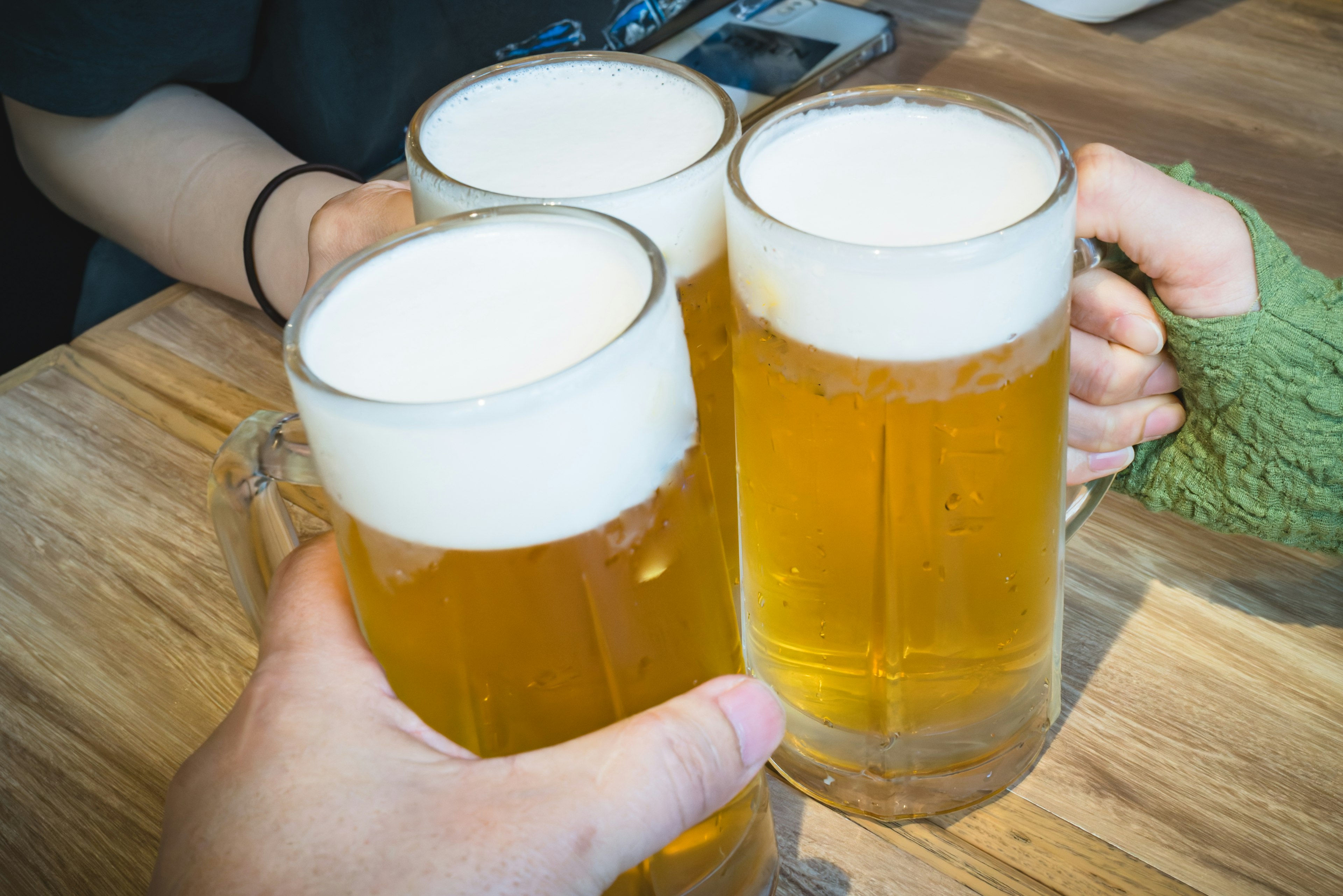 Group of hands toasting with beer mugs