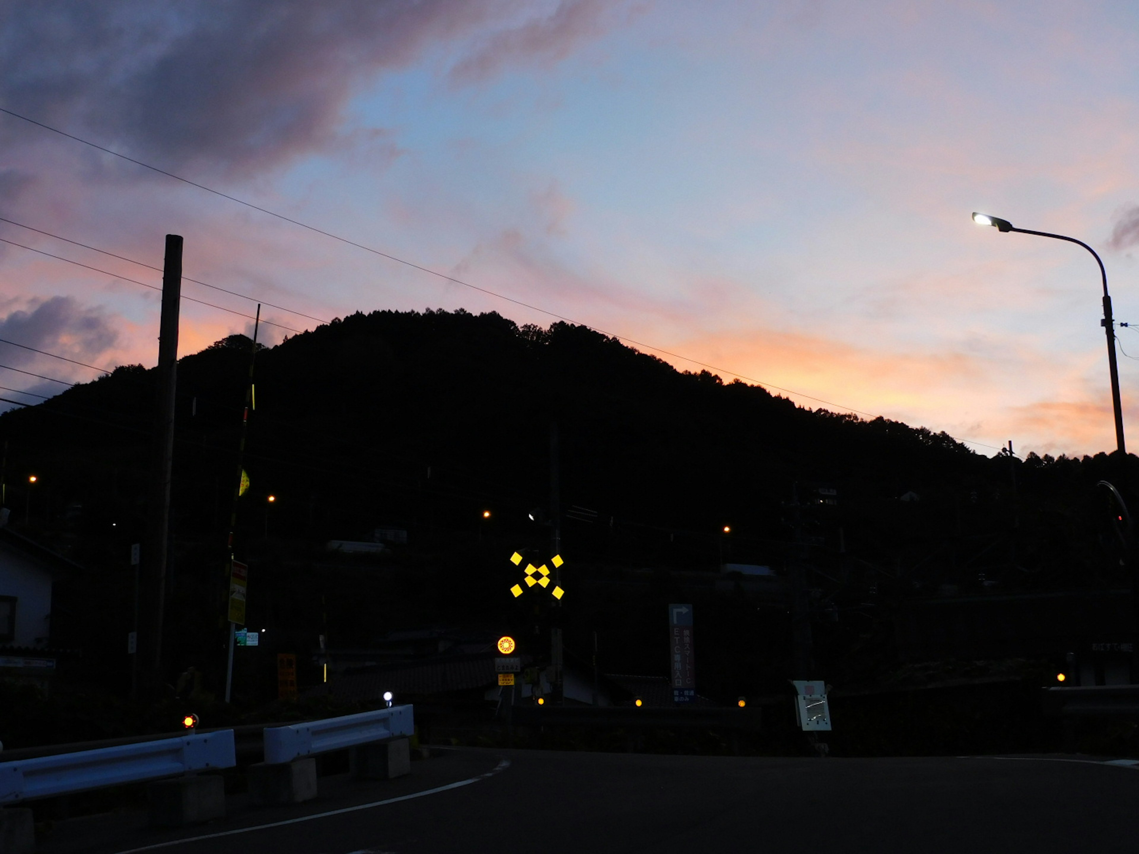 Montaña en silueta contra un cielo de atardecer con farolas