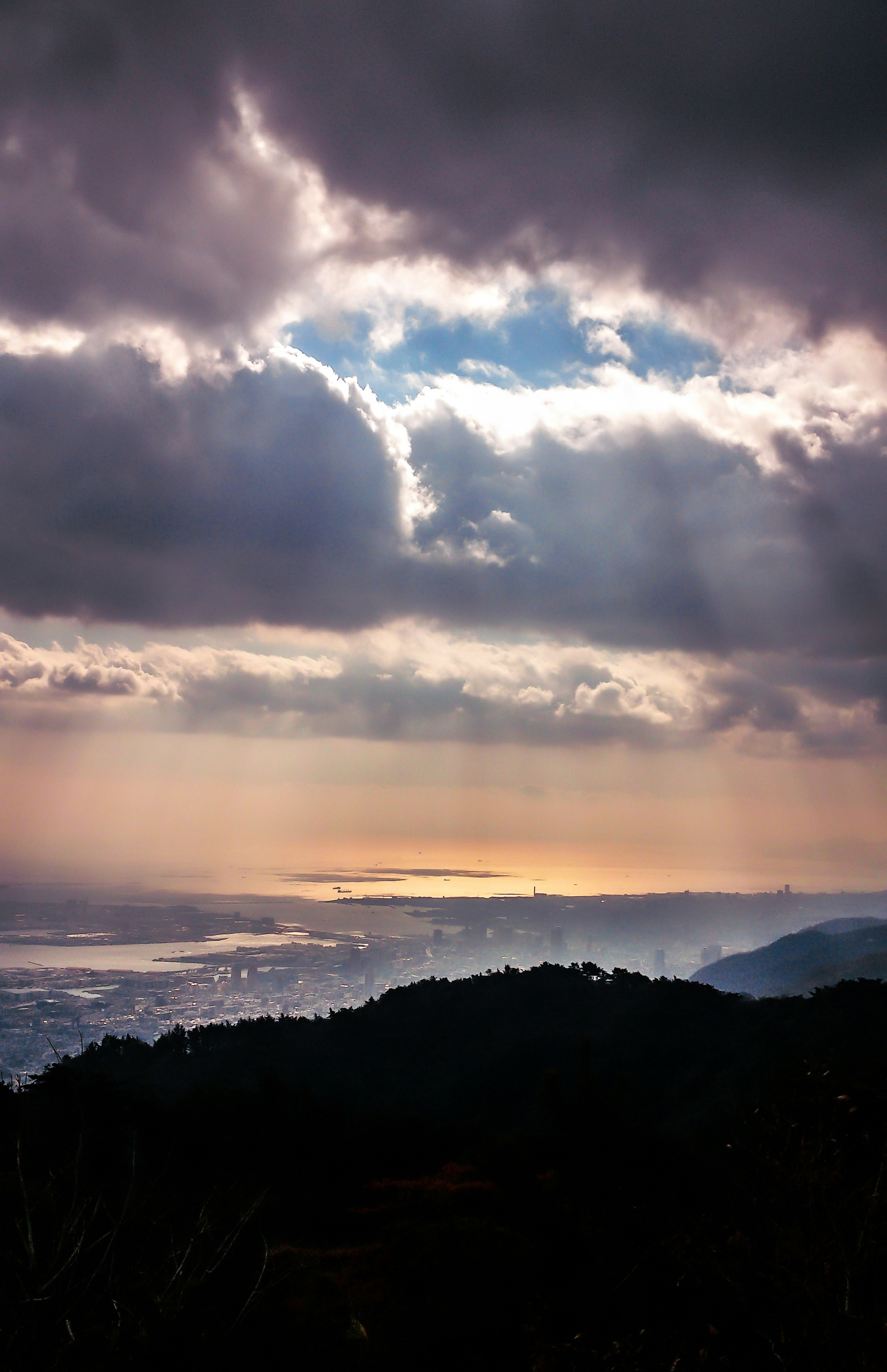 Dramatic sky with sunlight breaking through clouds overlooking mountains and sea