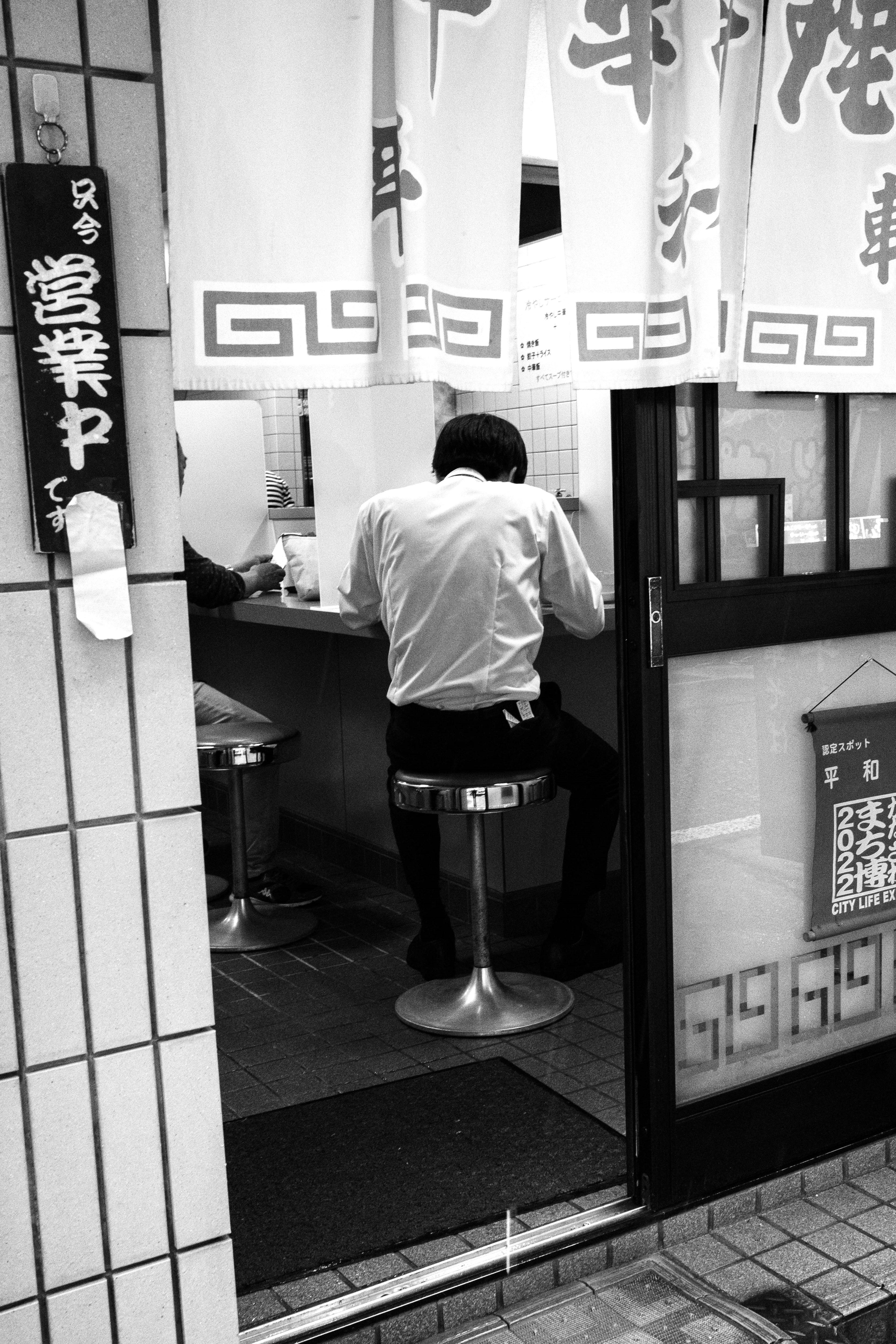 A black and white photo of a man sitting at a counter