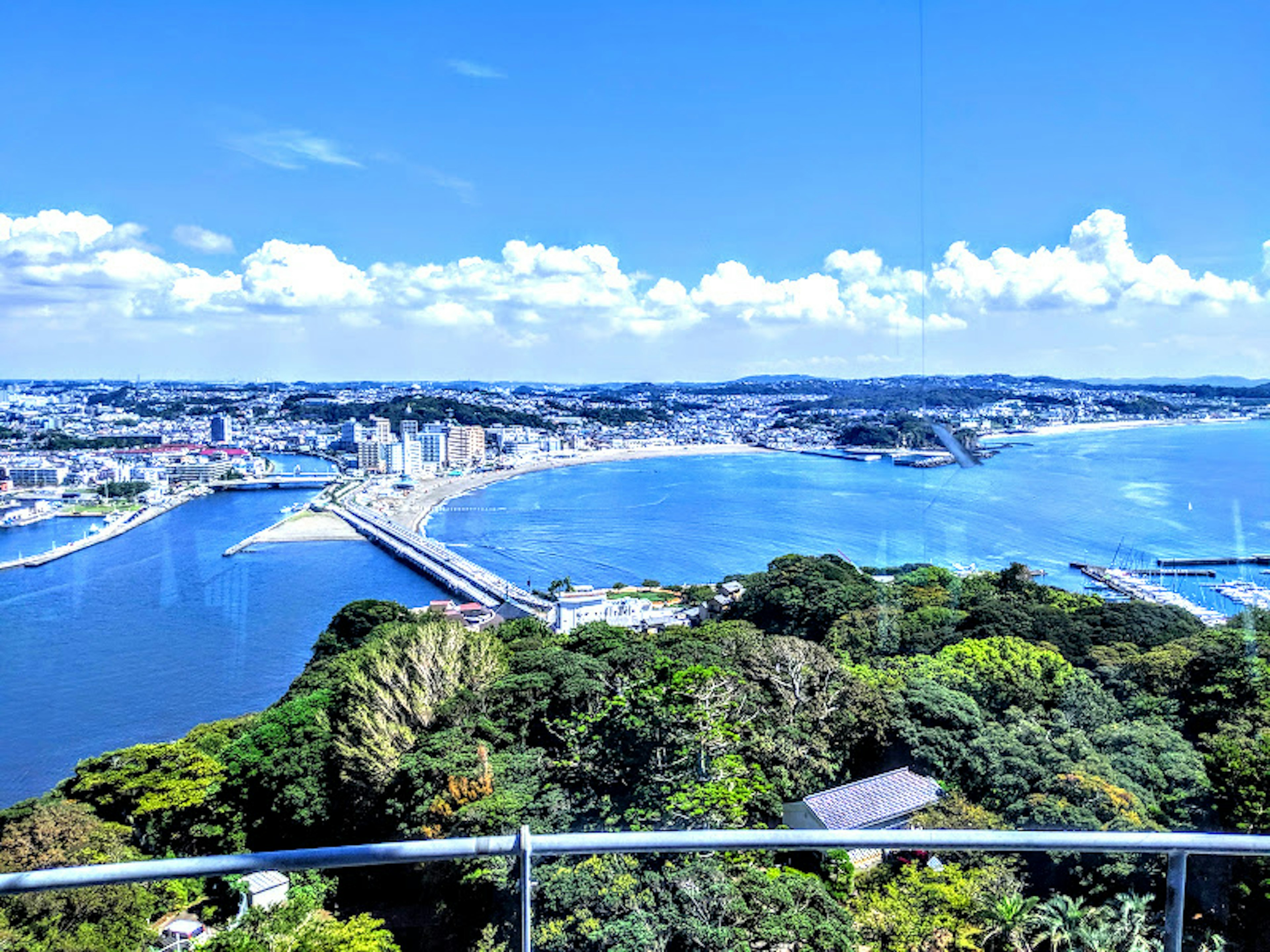 Panoramic view of a coastal city with blue waters and lush greenery