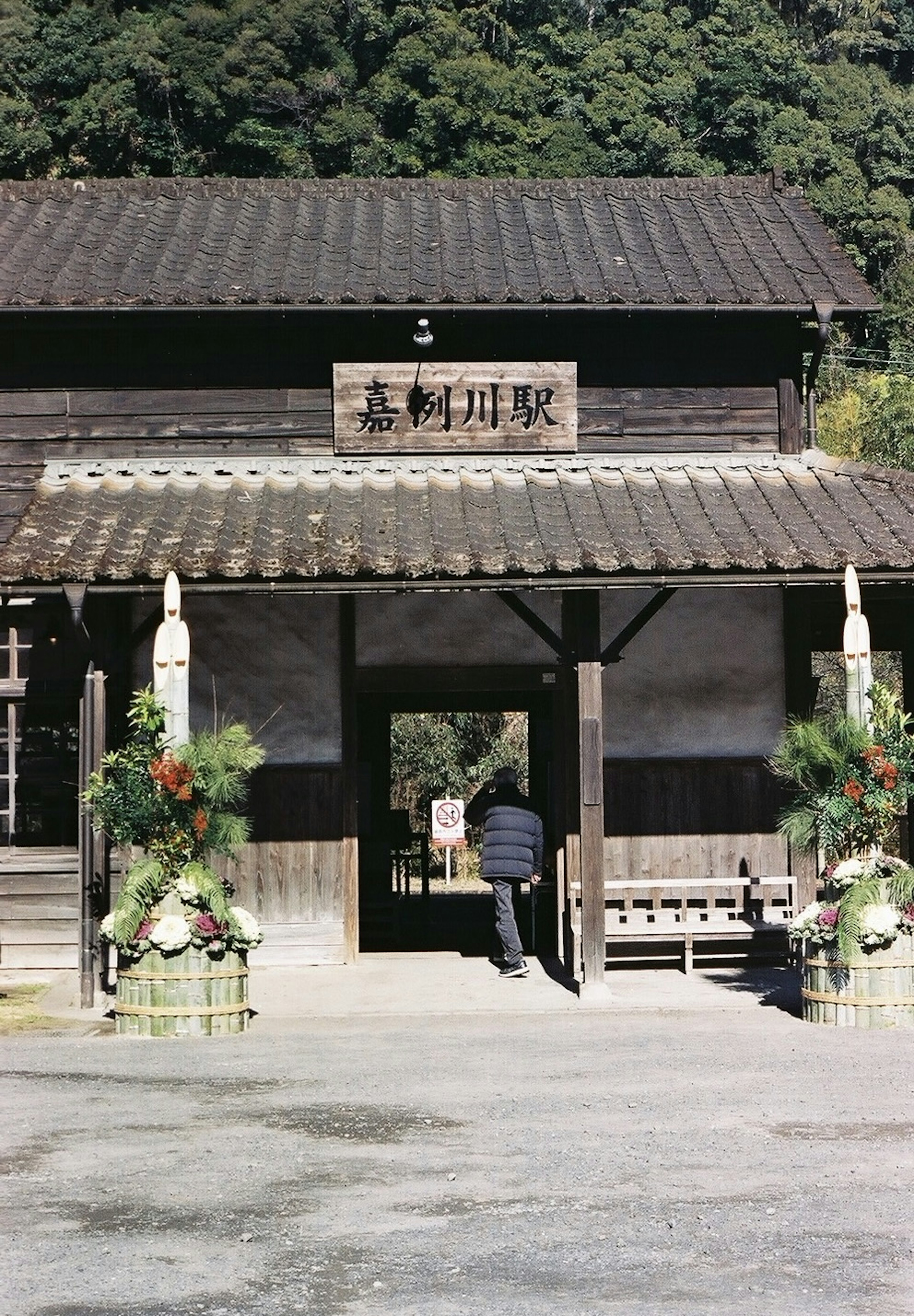 伝統的な日本の建物の入口に立つ男性と美しい装飾の花