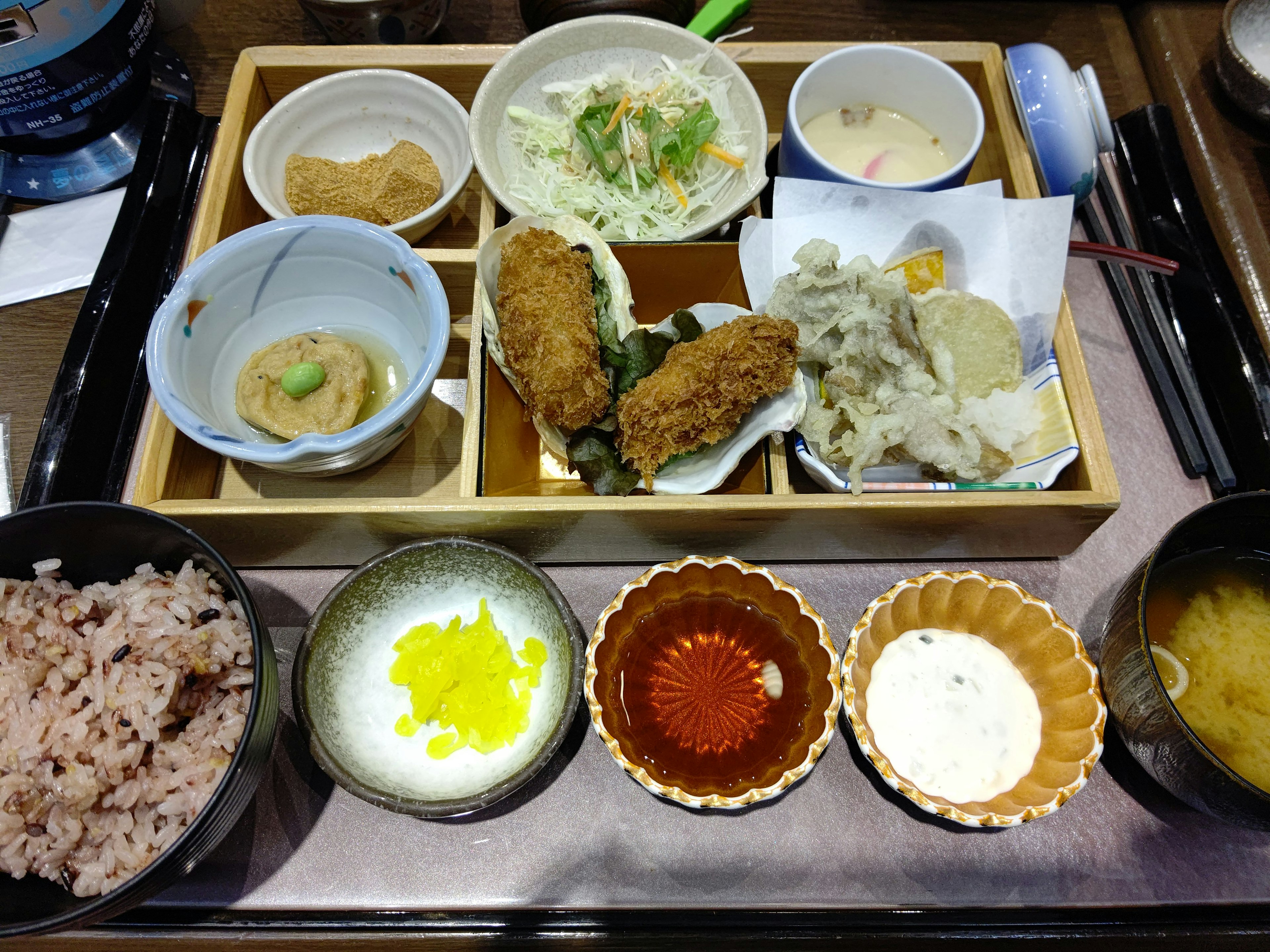 A Japanese set meal featuring fried items, salad, rice, and miso soup