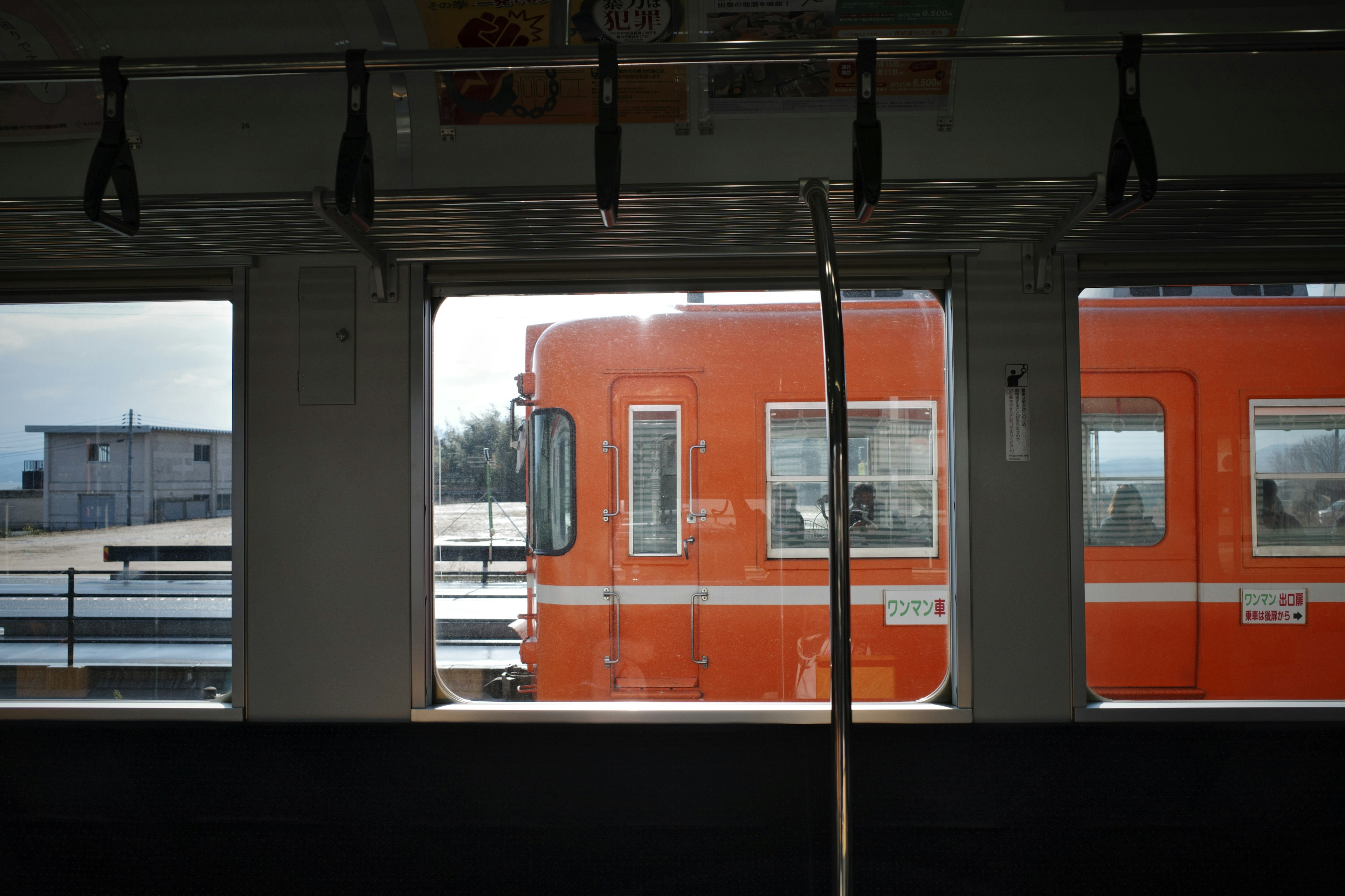 Interior view of a train with an orange train visible through the window