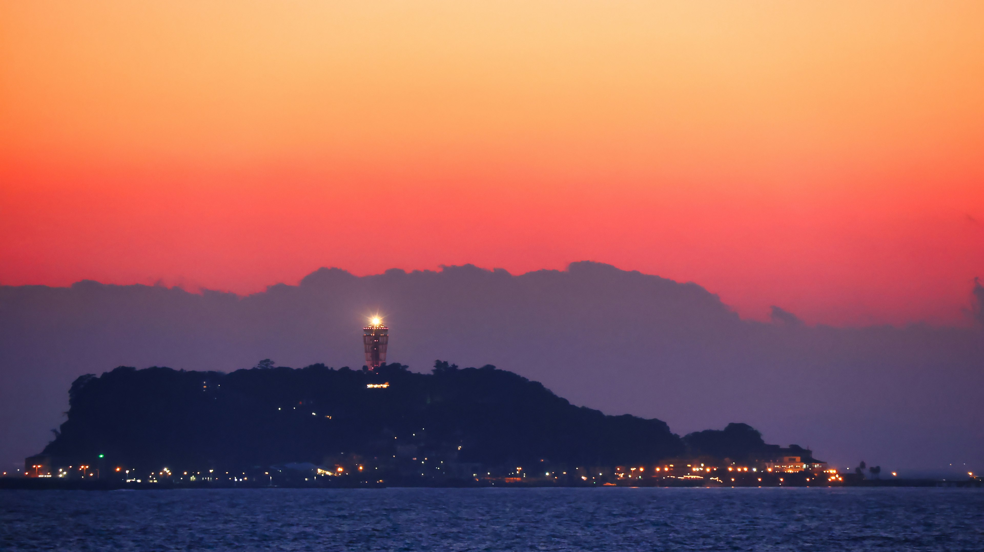 Paisaje de isla con faro brillando al atardecer