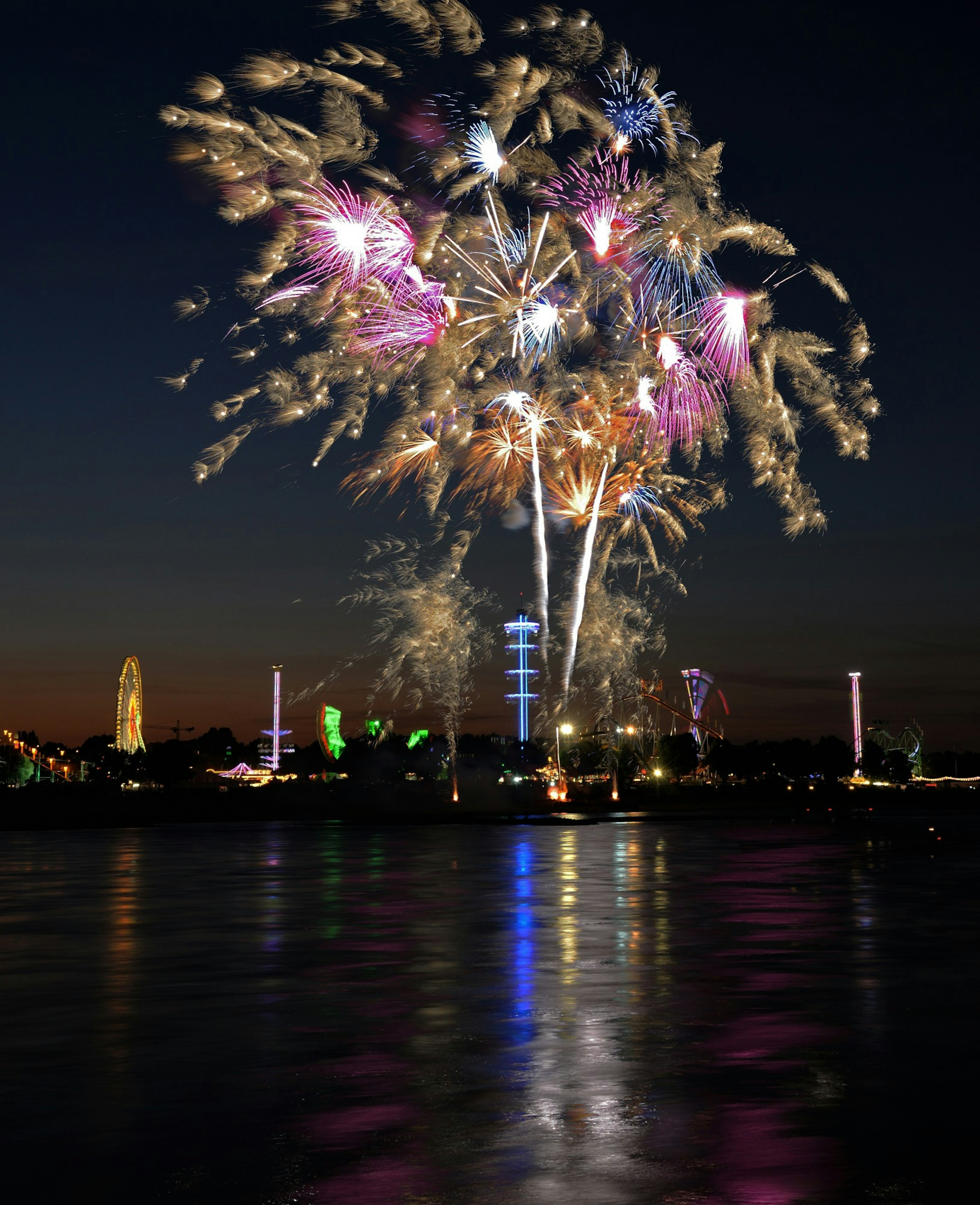 Colorful fireworks display over a calm body of water at night