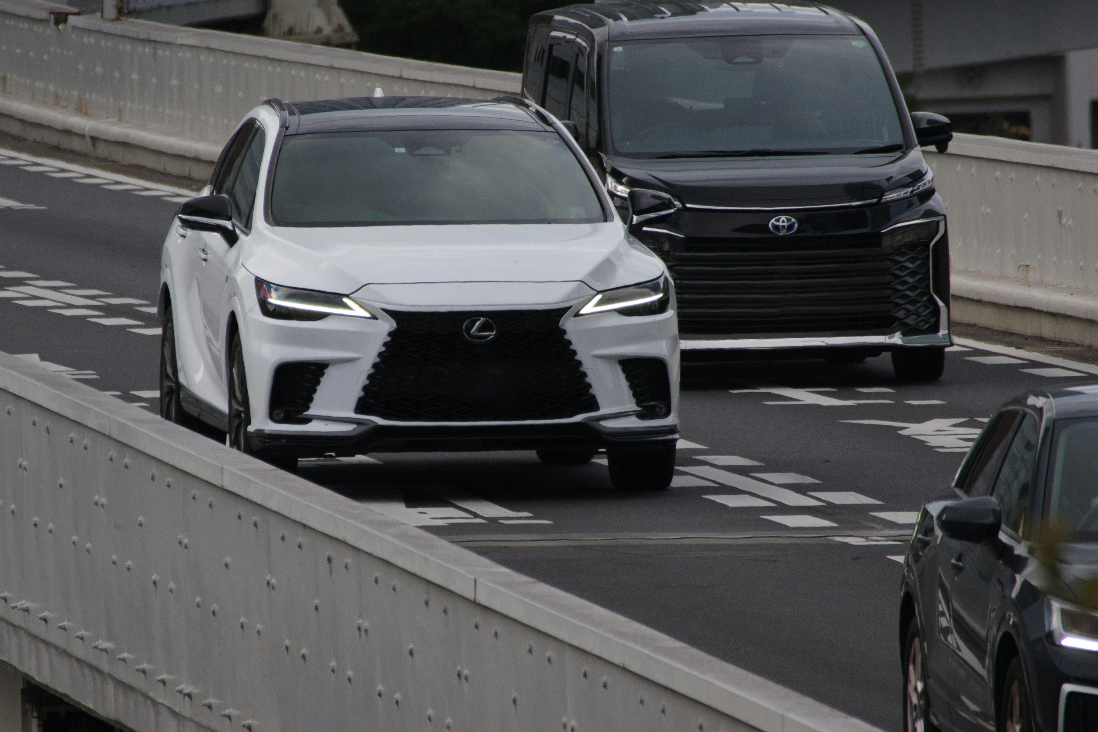 Un veicolo Lexus bianco che guida su un'autostrada con un veicolo nero accanto