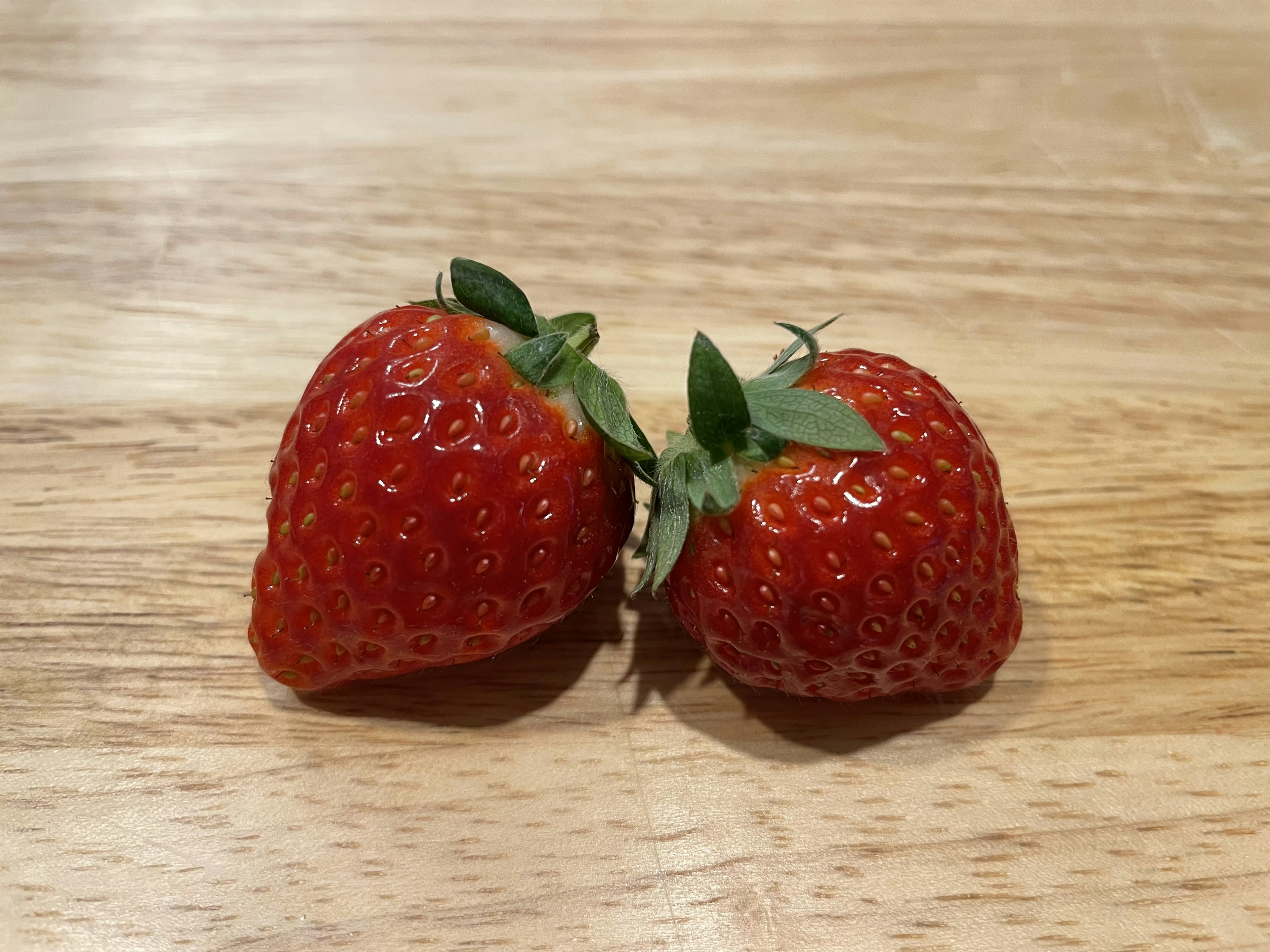 Two fresh strawberries on a wooden table