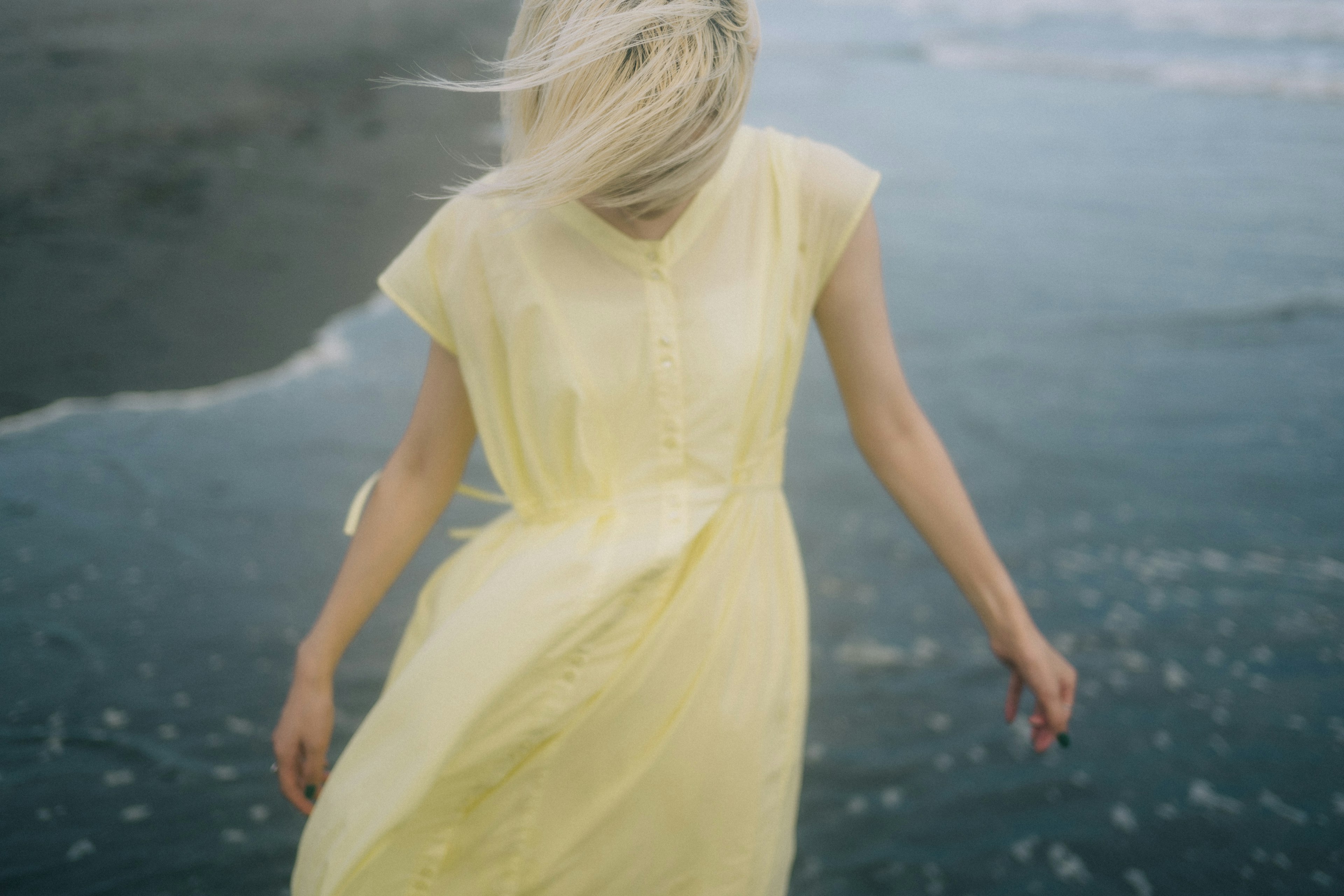 Femme en robe jaune flottante au bord de la mer