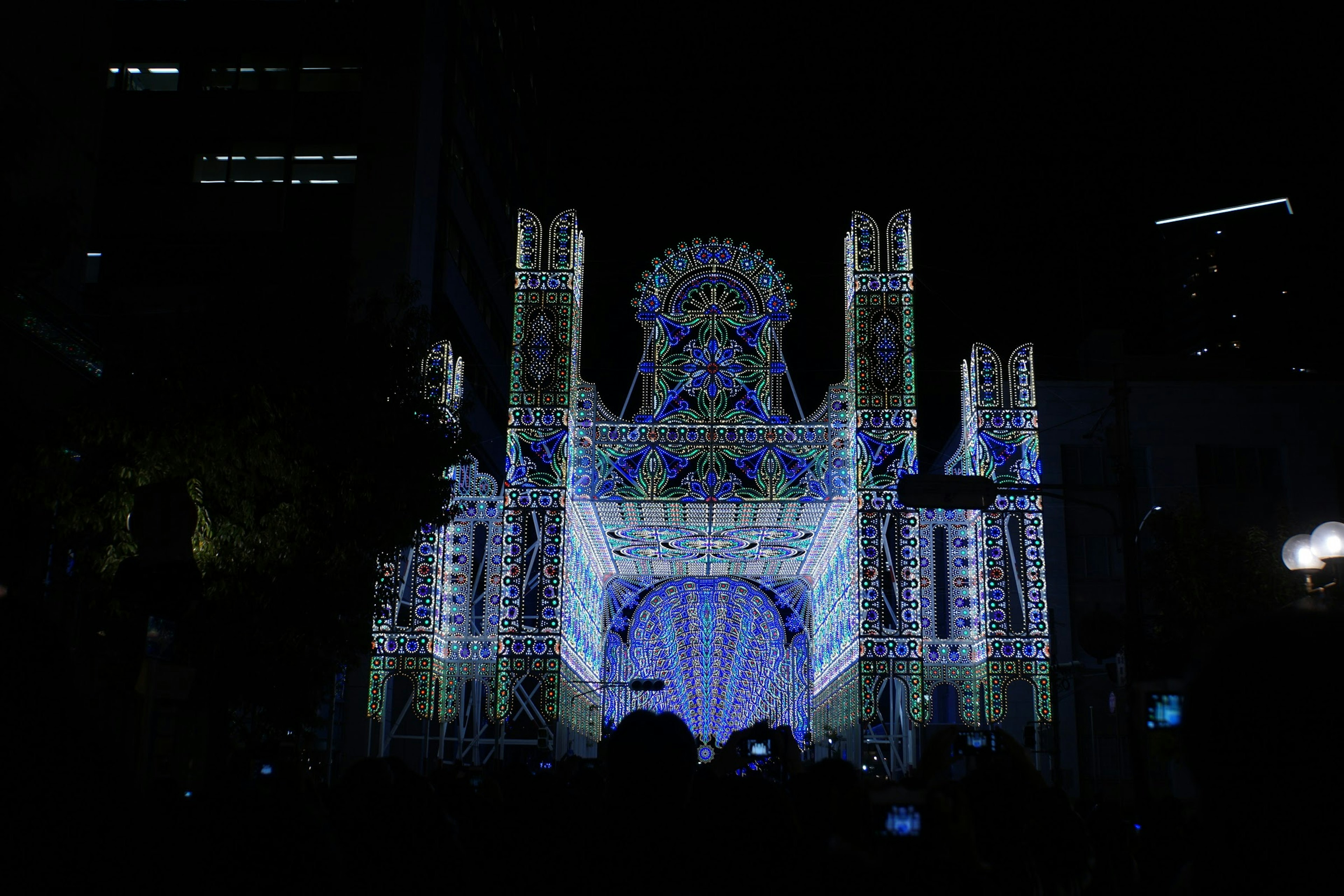 Illuminated cathedral facade at night decorated with blue and white lights